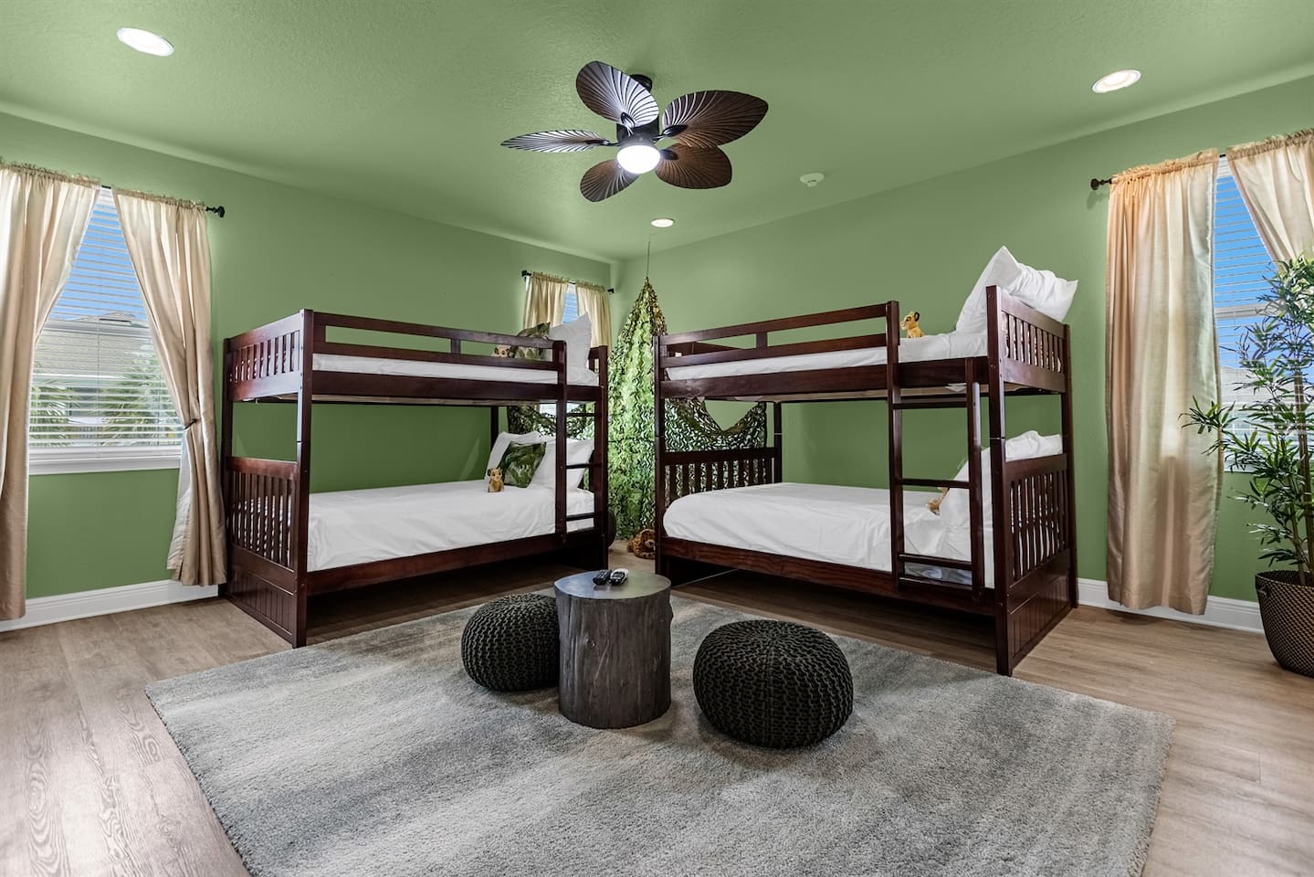 In the center of the room, two sturdy wooden bunk beds are arranged against one wall. The beds are draped in bedding with playful patterns of jungle leaves and animal prints, creating a cozy and adventurous atmosphere.