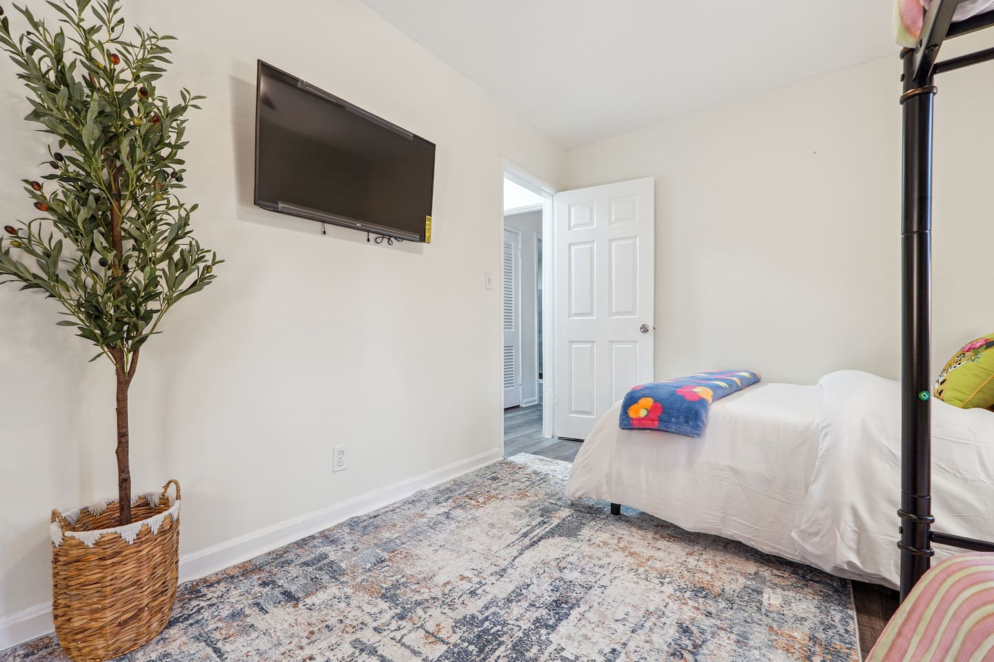 A cozy bedroom featuring a double bed, a bunk bed, a window, a bedside shelf with a lamp, and a TV — perfect for families or groups to relax and unwind.
