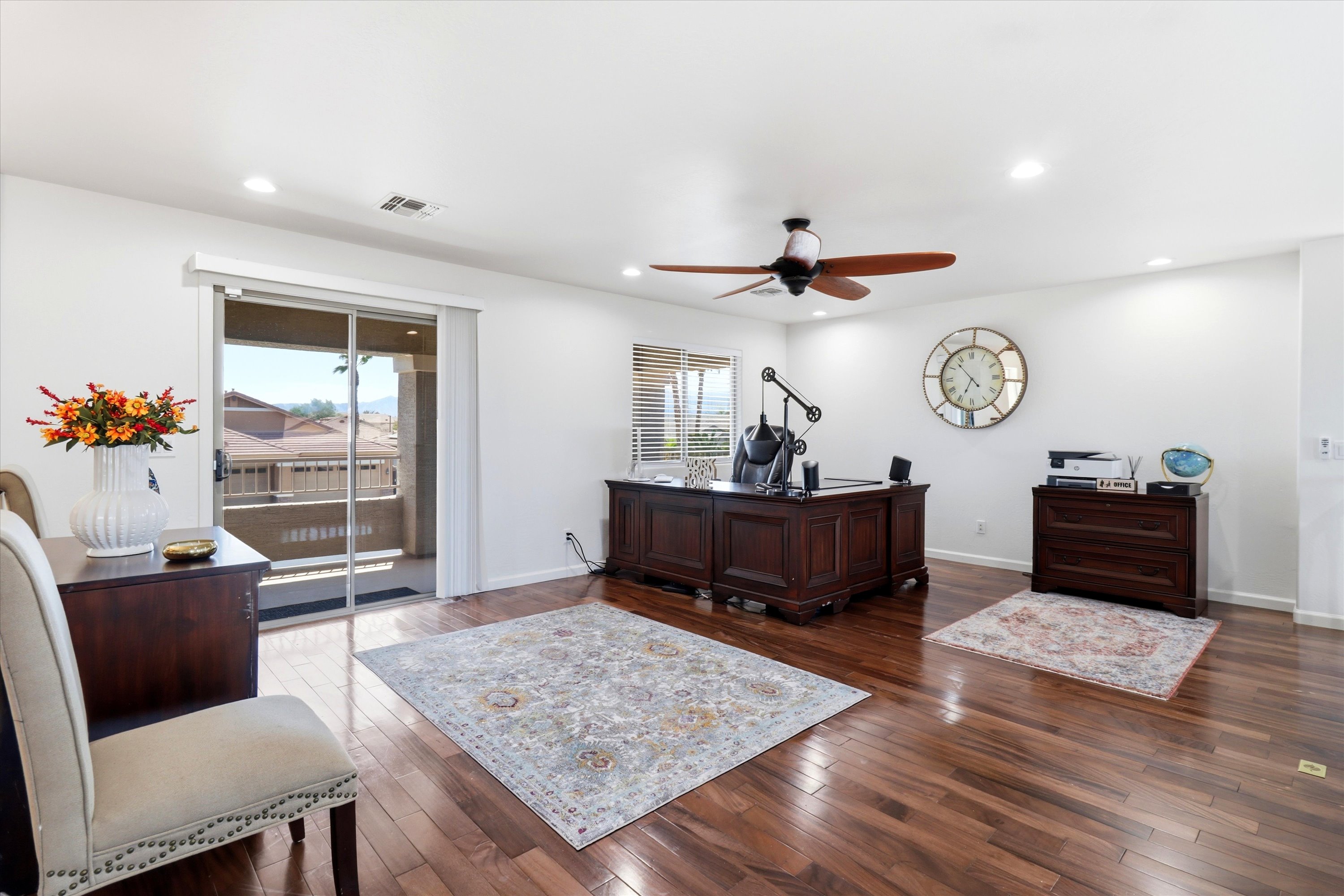 Home office with a large desk, wood floors, balcony access, and plenty of space to work.