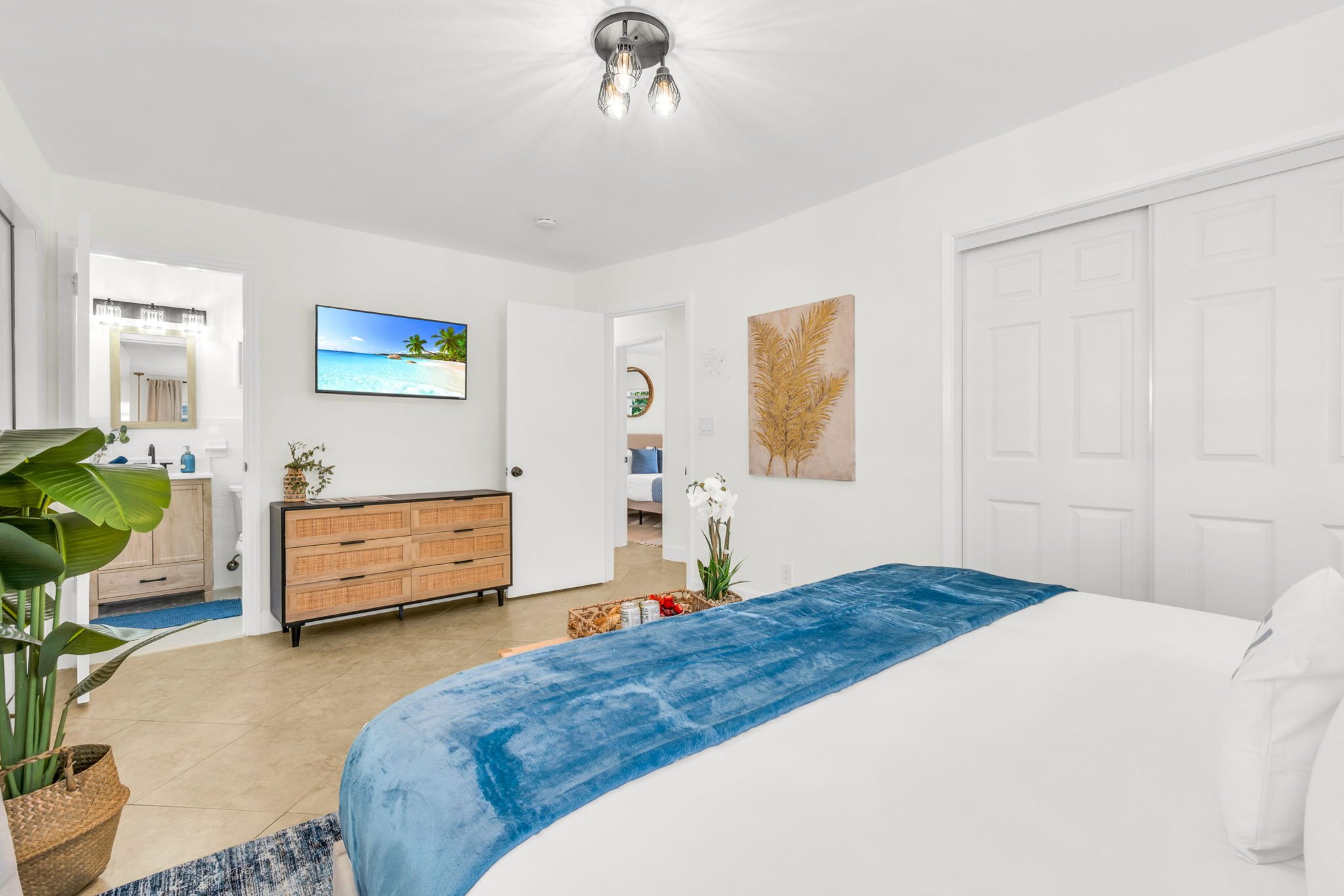 A bright and inviting primary suite featuring a hotel-quality king bed, dramatic pendant lighting, a sleek ensuite shower bath, and a Smart Fire streaming TV—your perfect private sanctuary.