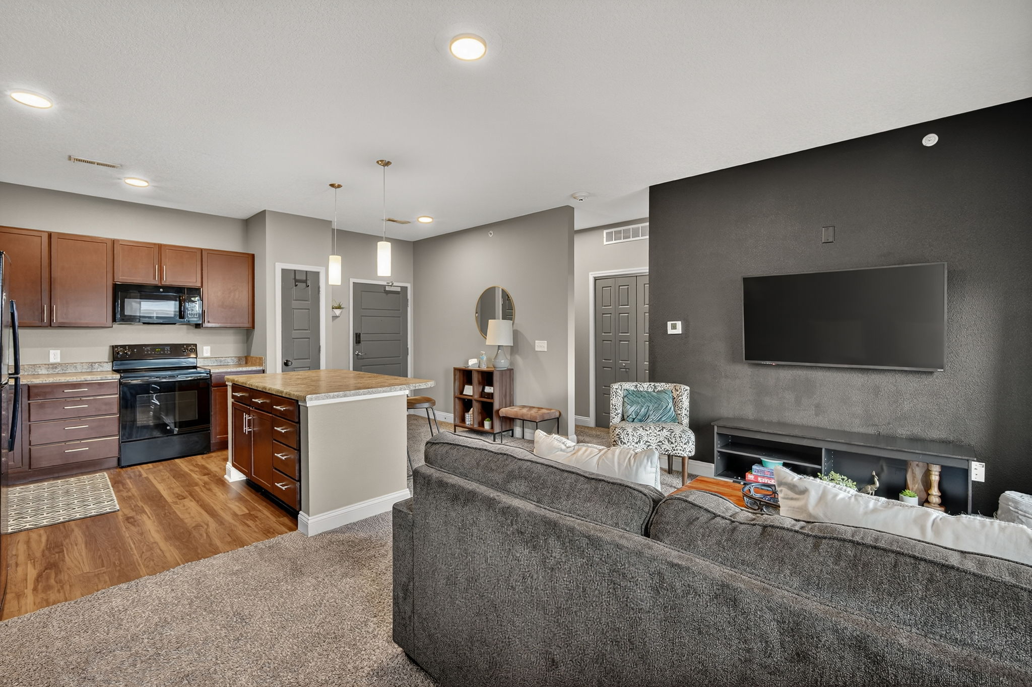Bright, modern kitchen with full-size appliances and ample counter space. Pendant lights highlight the central island, perfect for coffee, cocktails, or casual meals. Convenient entryway adds