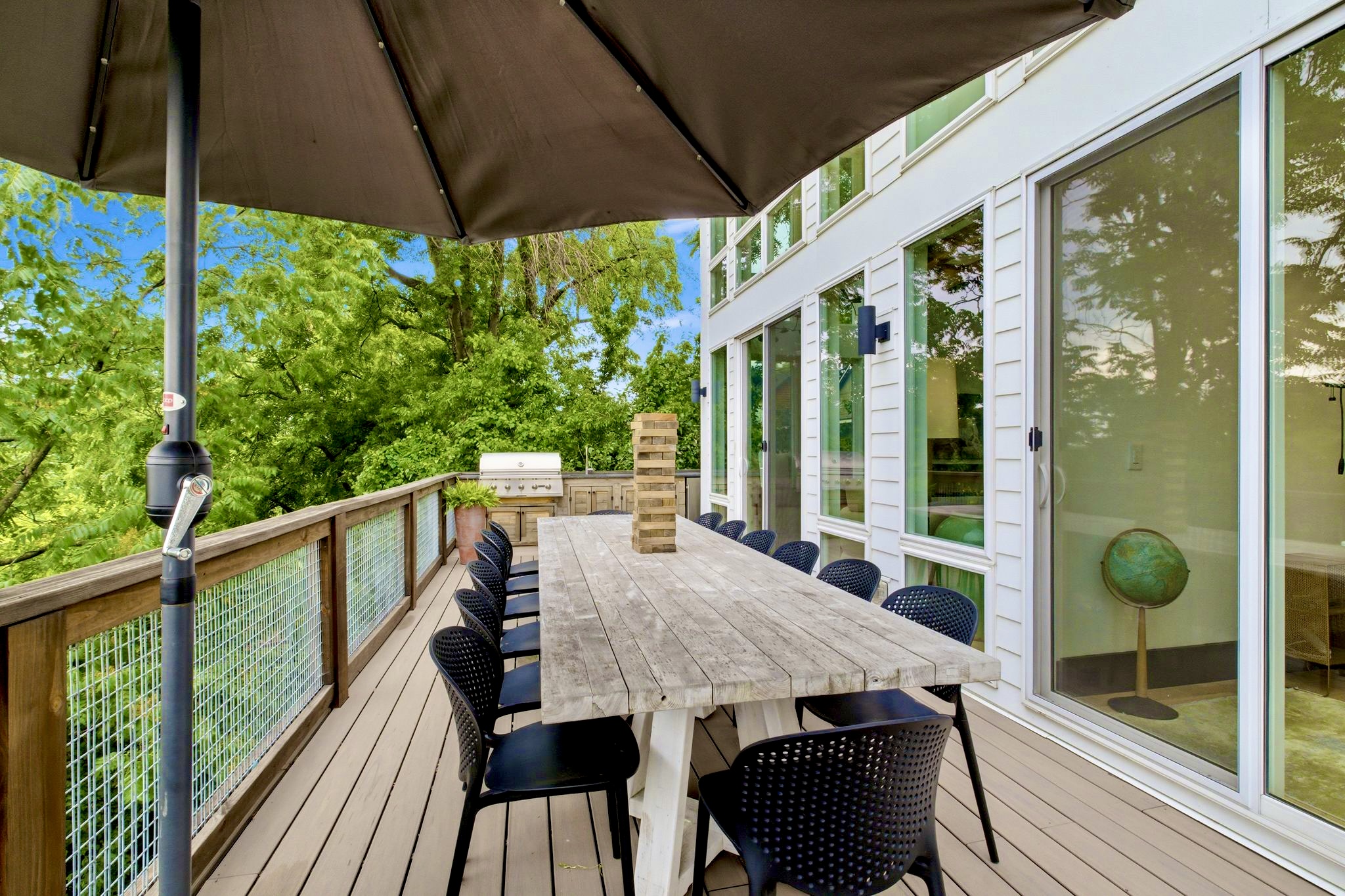 Covered deck w/ a long dining table, string lights & treetop privacy for relaxed outdoor evenings.
