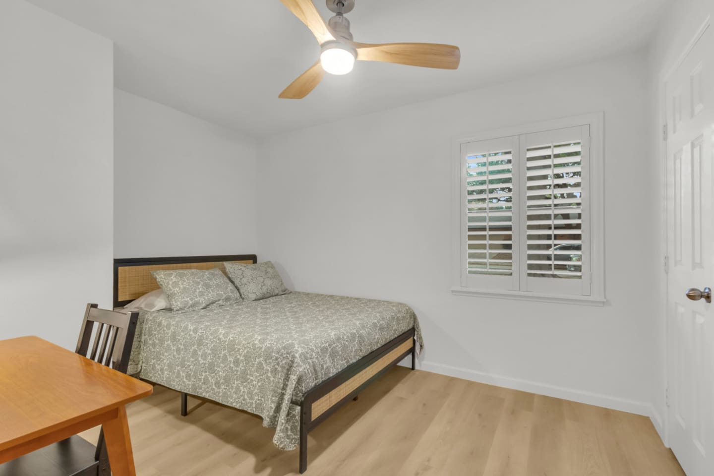 Comfortable guest room with queen bed, ceiling fan, and a dedicated workspace with desk and chair. Perfect for remote work during your stay.