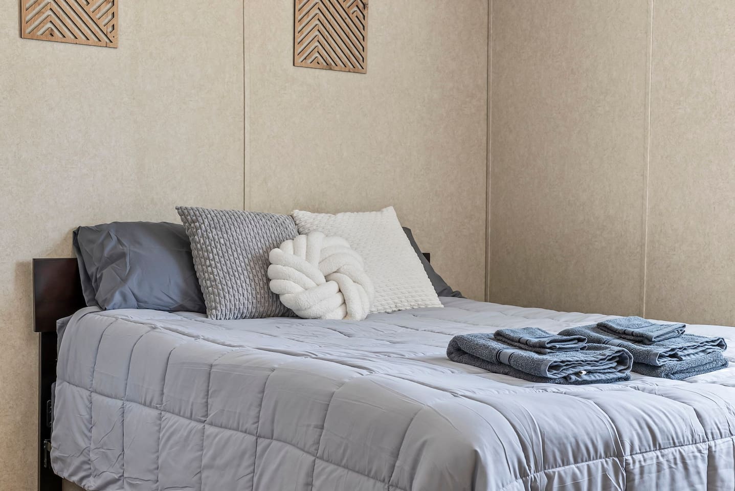 Inviting sleeping area featuring plush bedding, decorative pillows, and neatly prepared towels for your stay.