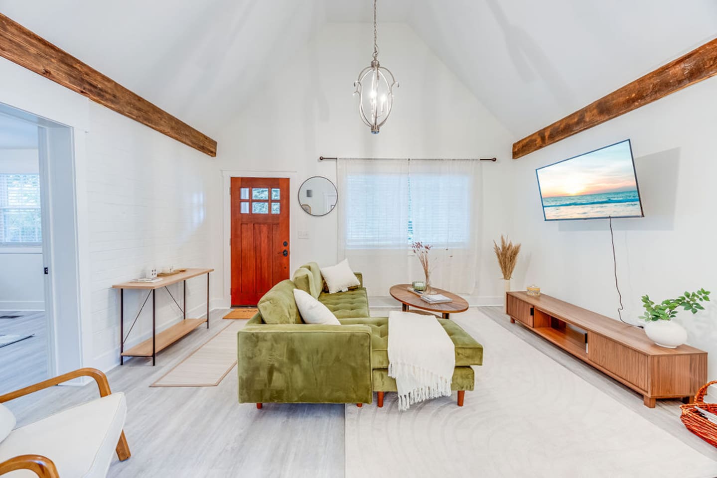 Spacious living area featuring a cozy couch, flat-screen TV, and an elegant chandelier, creating a perfect blend of comfort and style.
