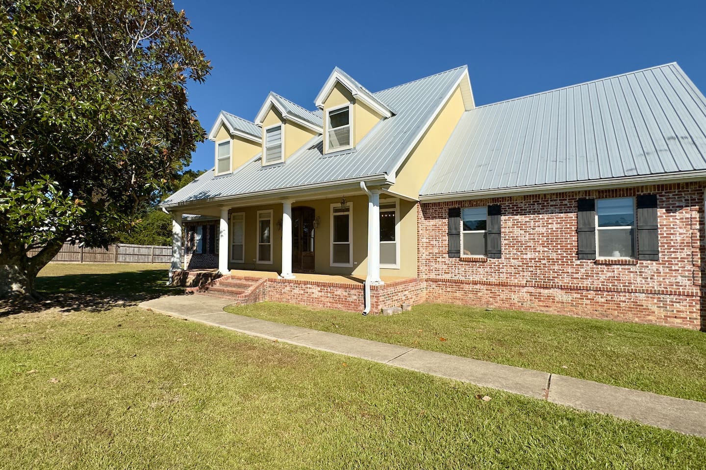 A well-kept lawn and mature tree frame the property, enhancing its cozy suburban charm.