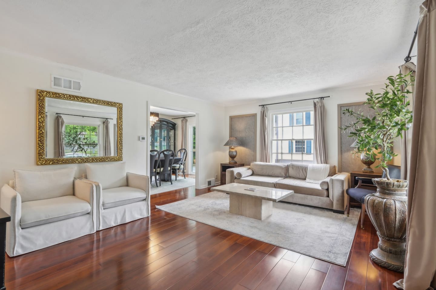 Relax in this bright, elegant living room with comfortable seating, warm wood floors, and plenty of natural light, an inviting space to unwind after a day out.