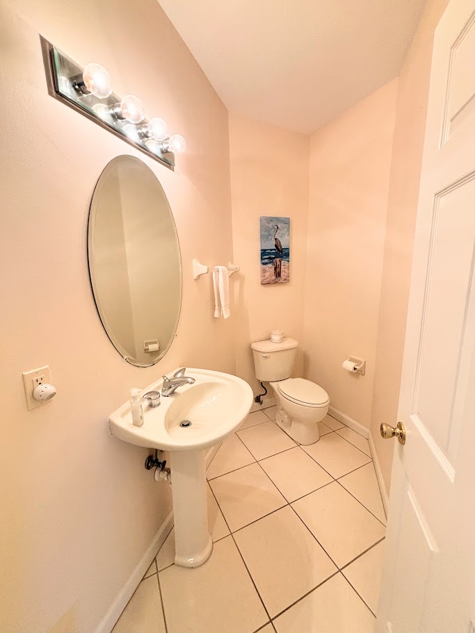 Convenient half bathroom with pedestal sink, tile flooring, and clean neutral finishes.