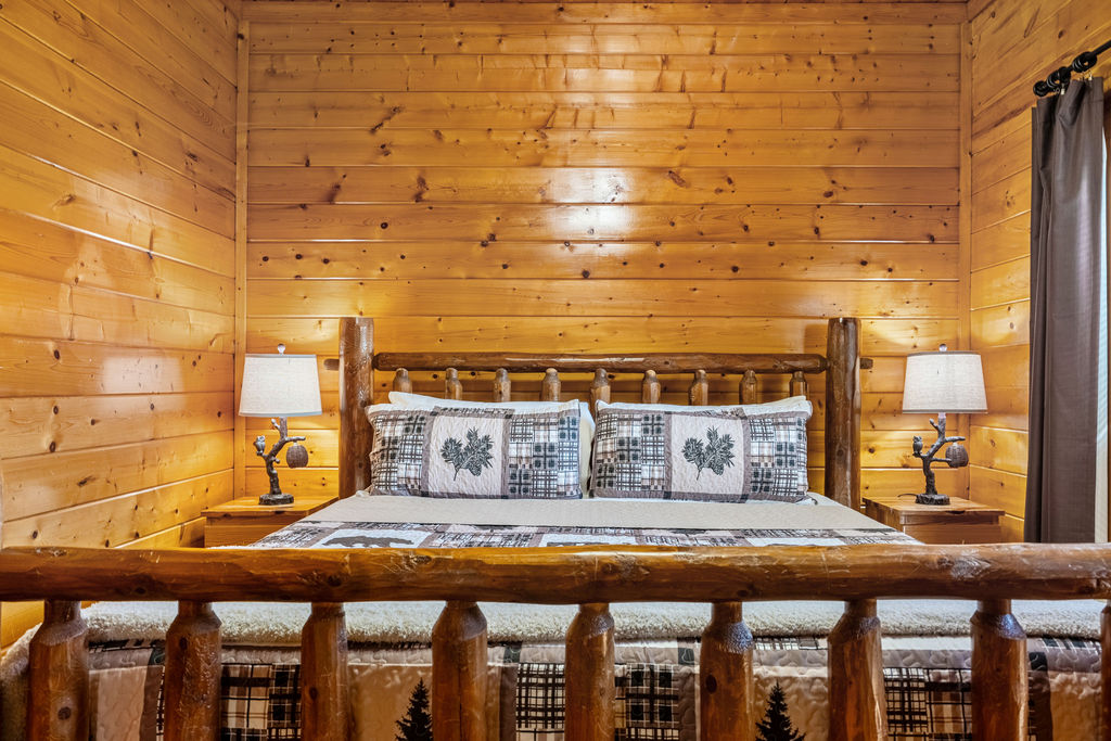 This inviting king bedroom offers plush comfort and forest views, sharing a conveniently located bathroom with the adjacent bunk room for a seamless group stay.