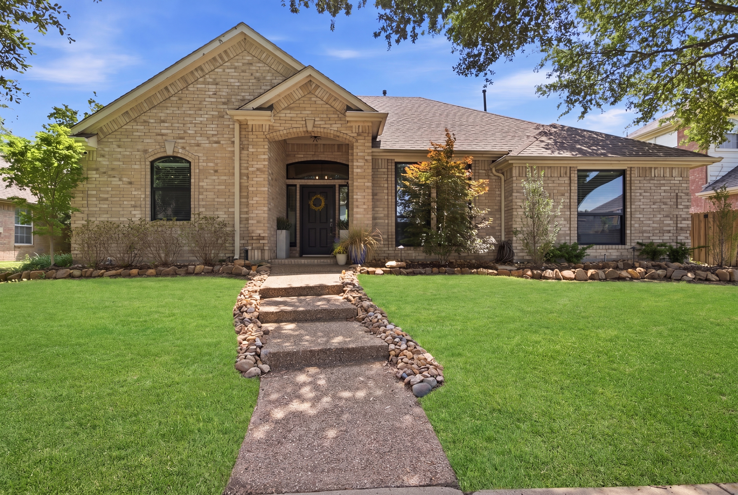 Welcoming brick Exterior with manicured landscaping, stone walkway, and a quiet residential setting in The Colony, minutes from Grandscape and Stonebriar Country Club.
