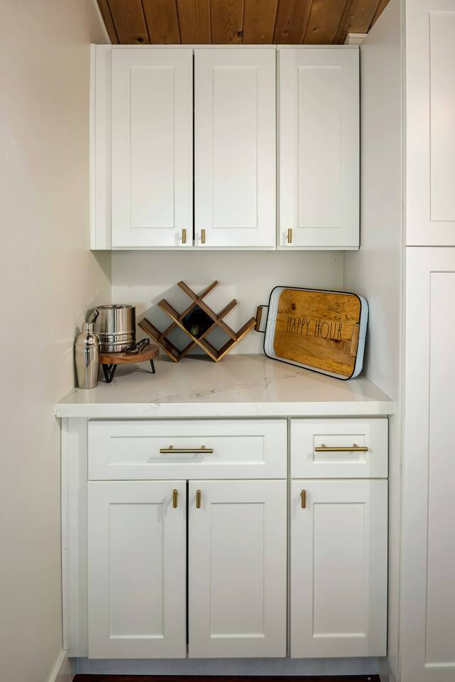 Minibar area with a wine rack, cocktail set, cocktail glasses (above), and a serving tray.