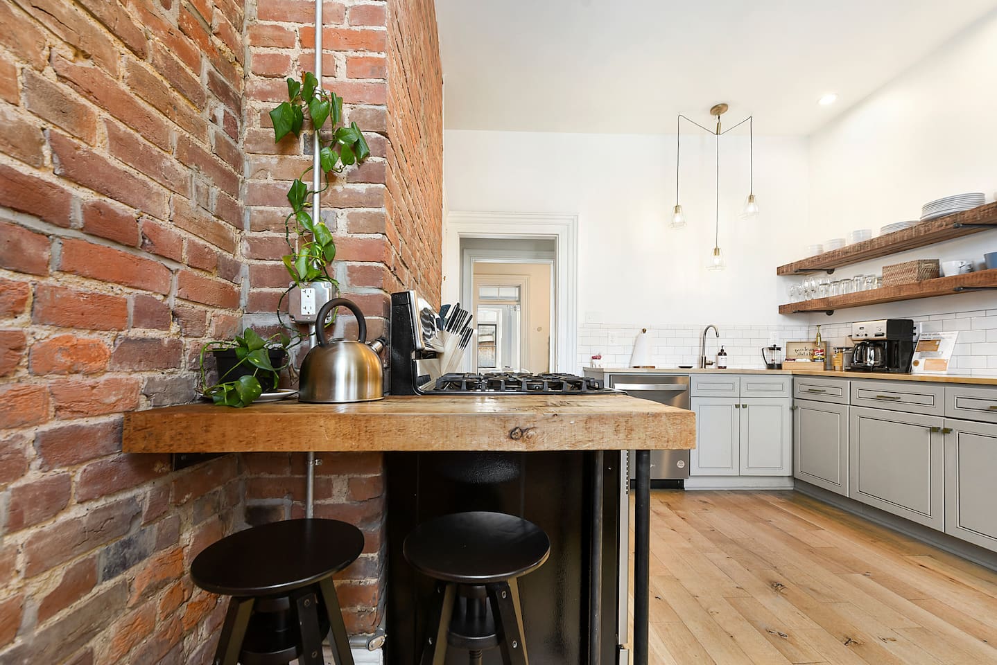 Enjoy a stylish kitchen with a cozy brick wall, fully equipped with cookware, appliances, and a coffee maker—perfect for your morning brew. Cook with ease and enjoy a warm, inviting space for your meals.