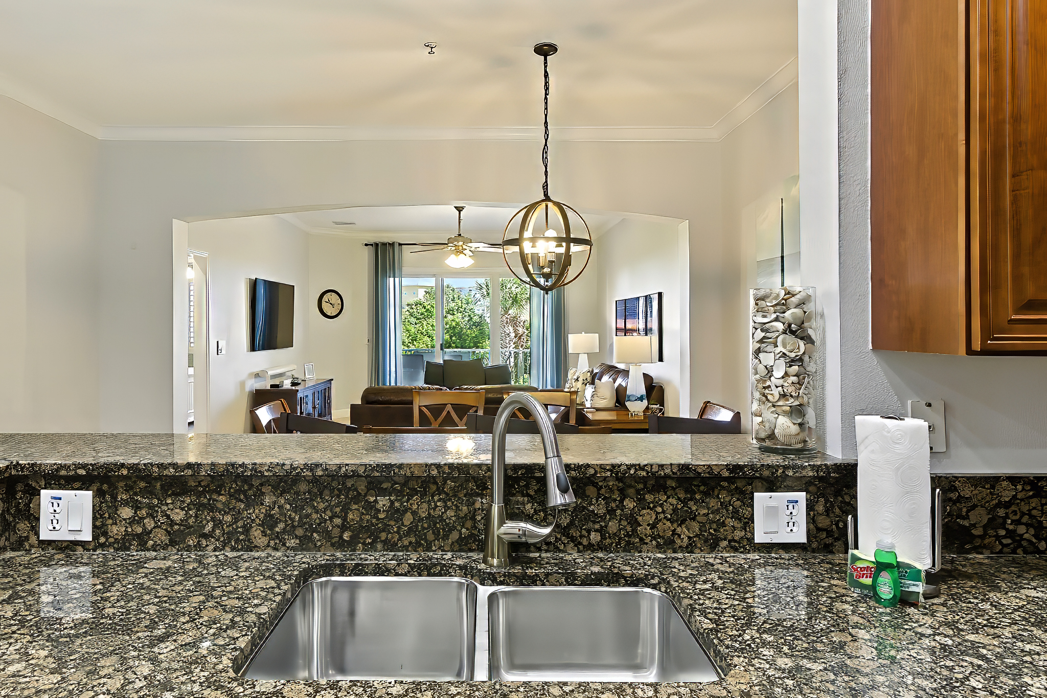 🍹🏝️ Open-concept island vibes—this kitchen flows right into the living room, so the chef never misses the fun. Enjoy granite countertops, a double sink, and the perfect view straight out to the relaxing coastal living space. ✨🍽️
