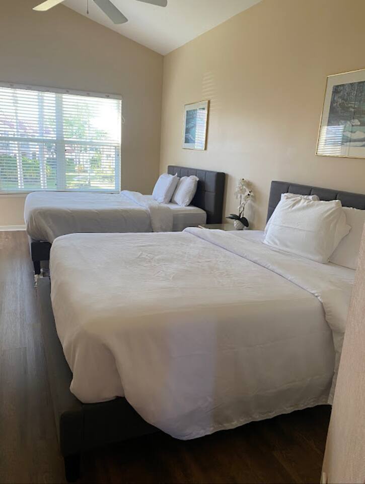 Bright bedroom featuring two beds, wood-look flooring, and a clean, relaxing setup.