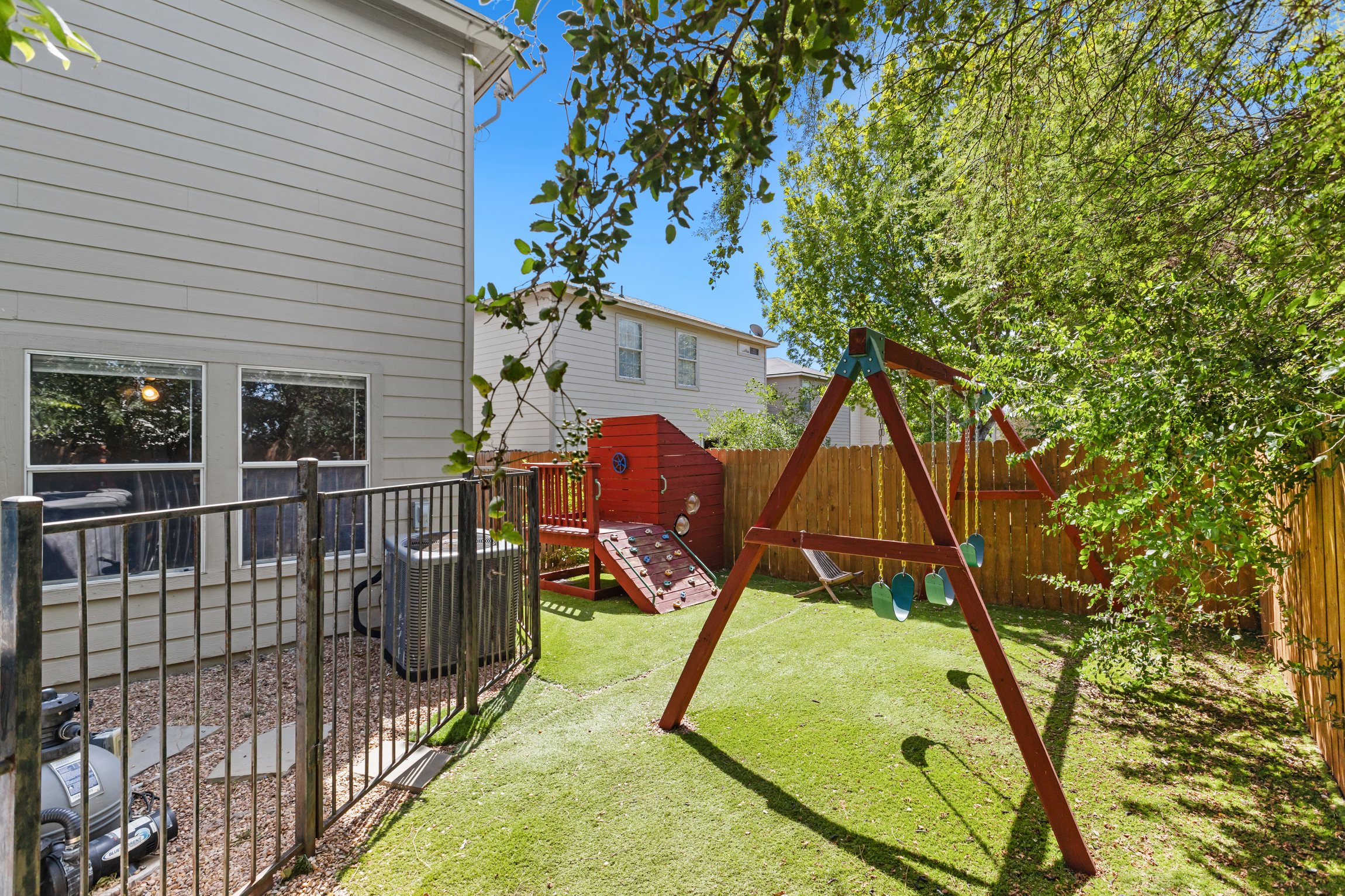 Backyard playground with swing set inside a fully fenced yard — a standout feature for families with young children. Safe, private, and right in your backyard at this Northeast San Antonio vacation rental.