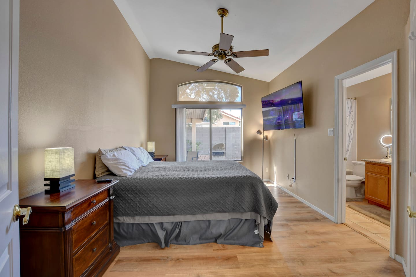 Serene primary suite with patio access, vaulted ceiling, TV & en‑suite.