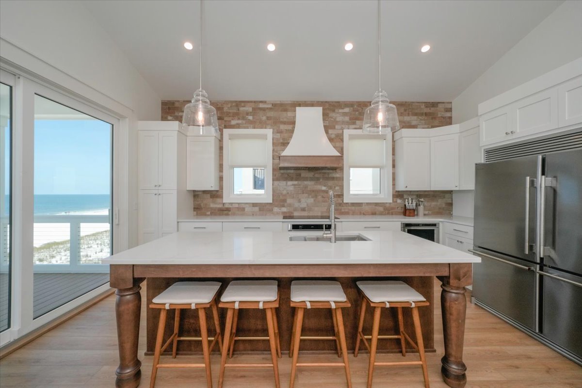 Top floor main kitchen with vaulted ceilings, dual refrigerators, induction cooktop, a reach in pantry for guests groceries, and all Kitchen Aid appliances.