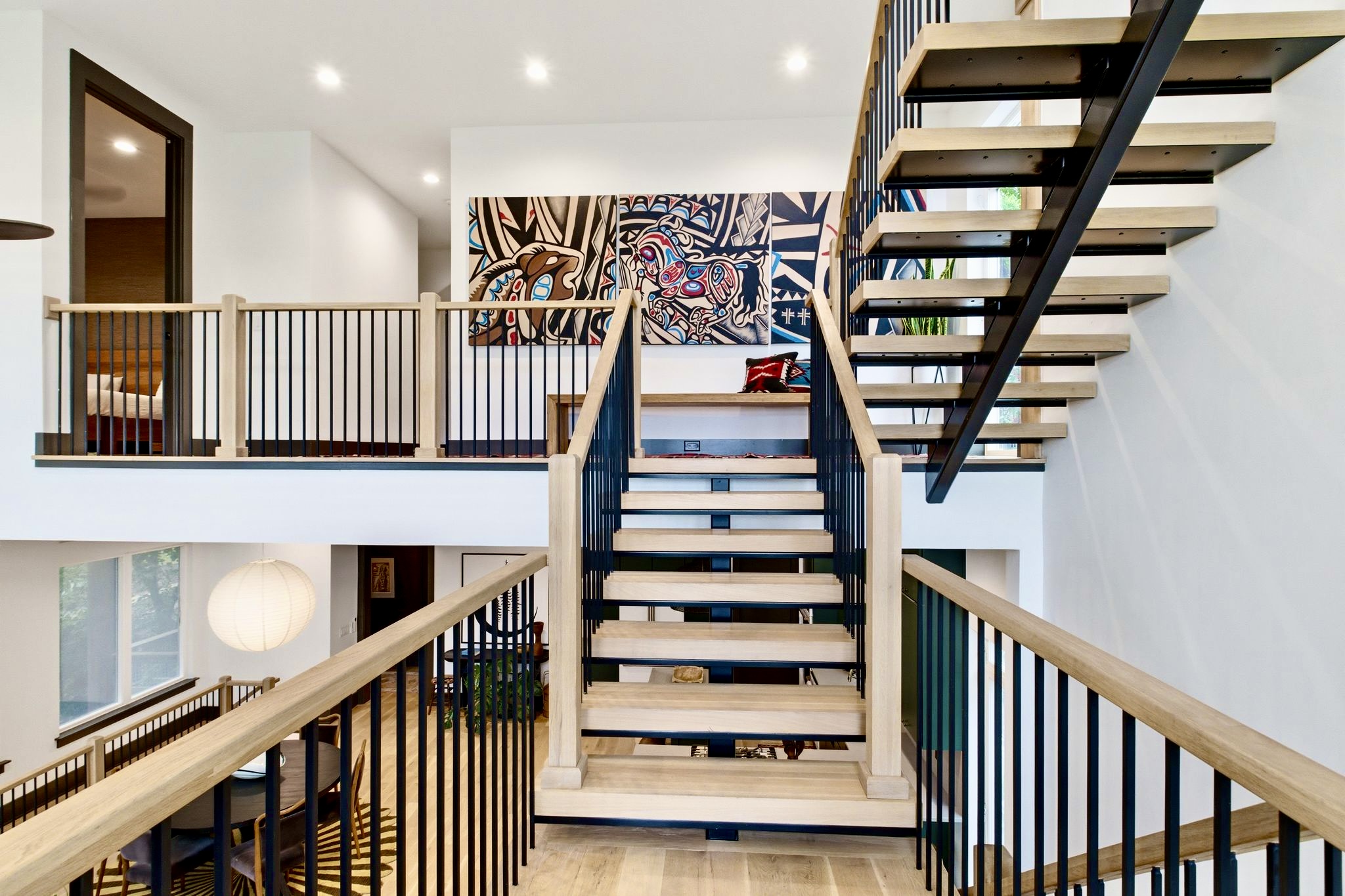 Striking black spiral staircase anchors this double-height space w/ bold architectural drama.
