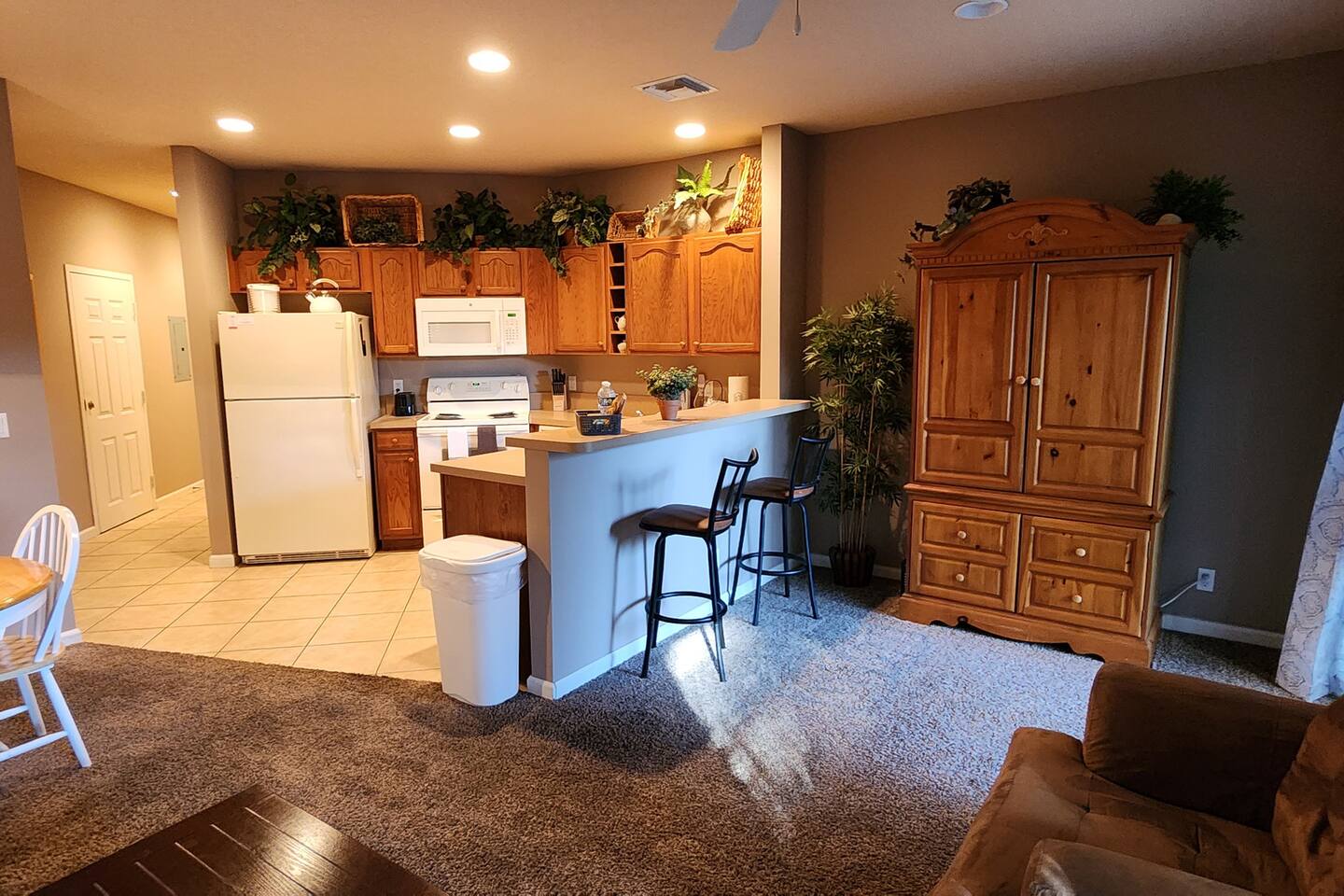 Bright open-concept kitchen and living area with full-size appliances, breakfast bar seating, and comfortable furnishings.