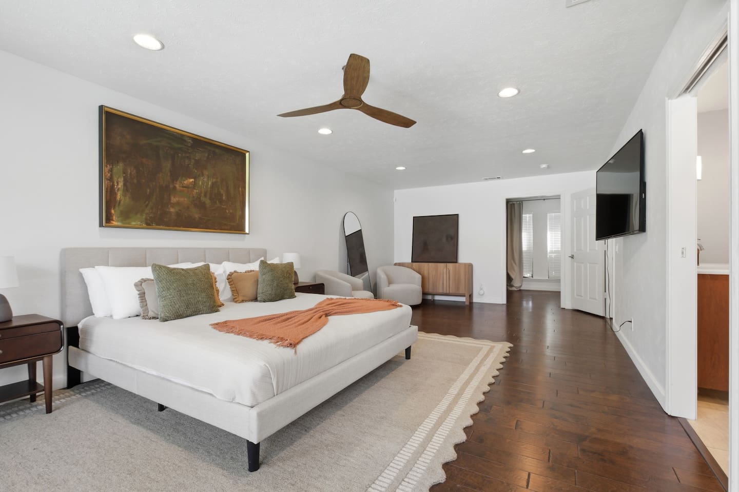Spacious primary bedroom featuring room-darkening shades, a comfortable sofa, and thoughtfully provided essentials for a relaxing and restful stay.