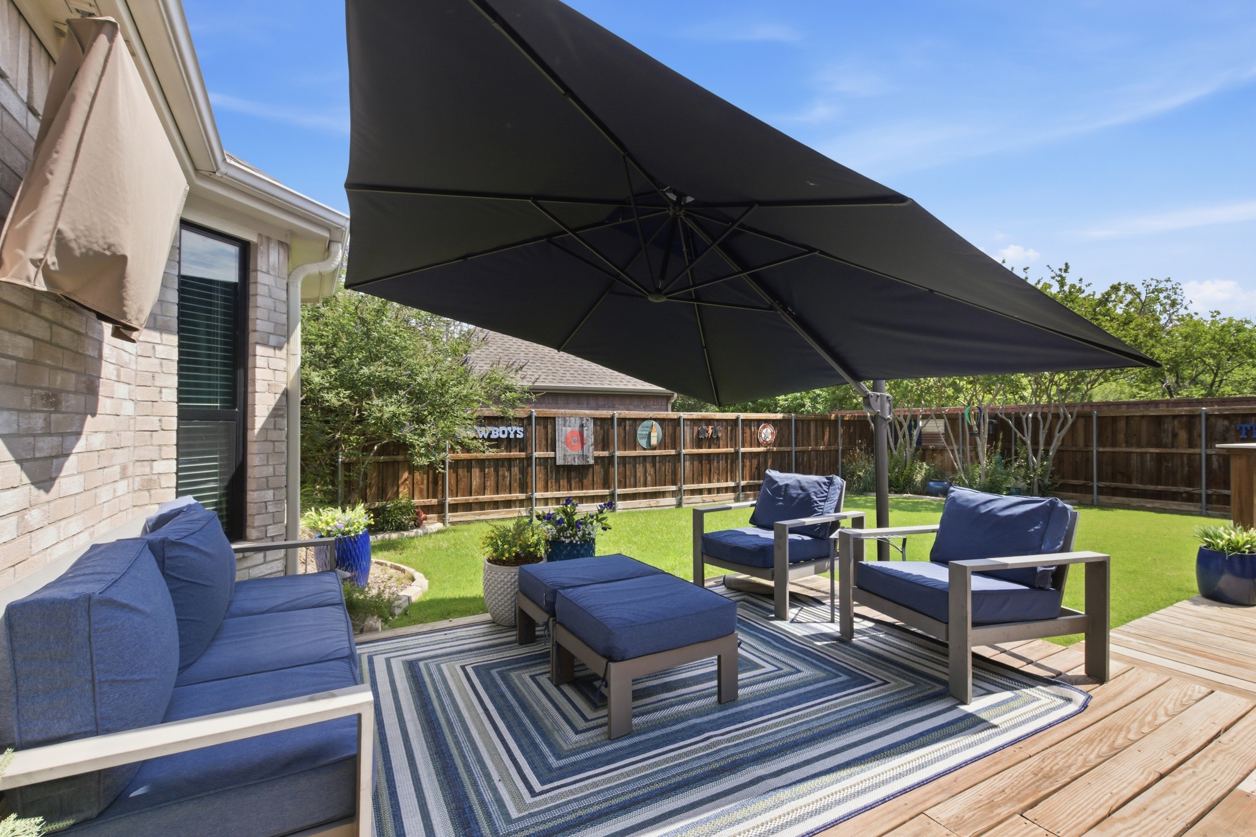 Wooden Deck with comfortable Outdoor Furniture, plush navy cushions, and a large shade umbrella for hot Texas afternoons.

