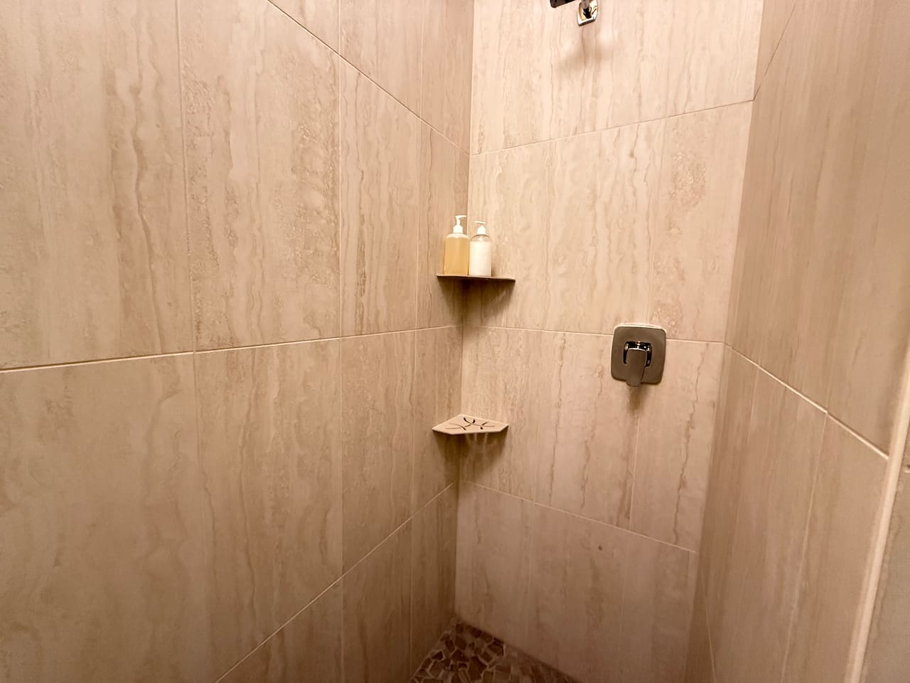 Newly renovated walk in shower with a river rock tile floor. 