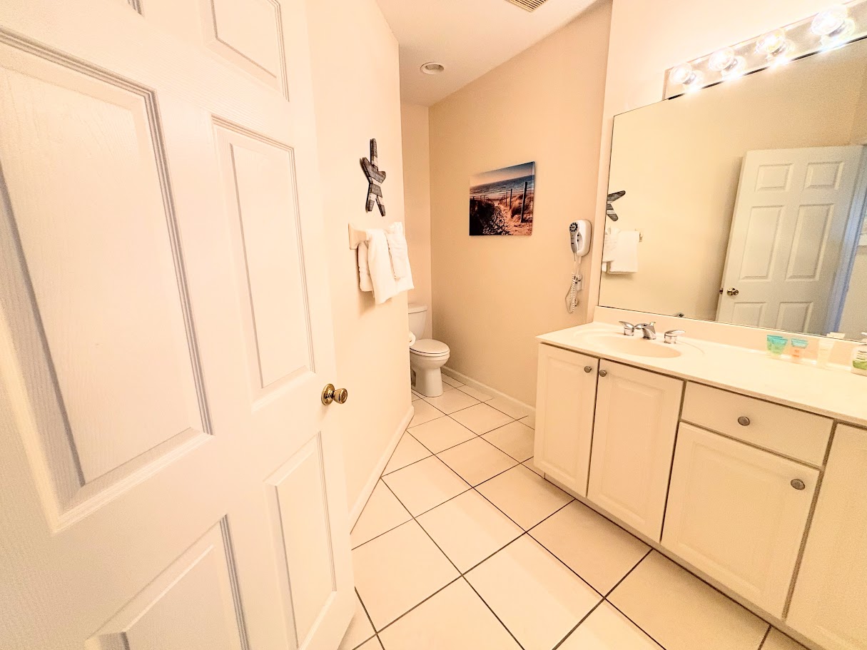 Clean and spacious bathroom featuring a large vanity, tile flooring, and neutral finishes.