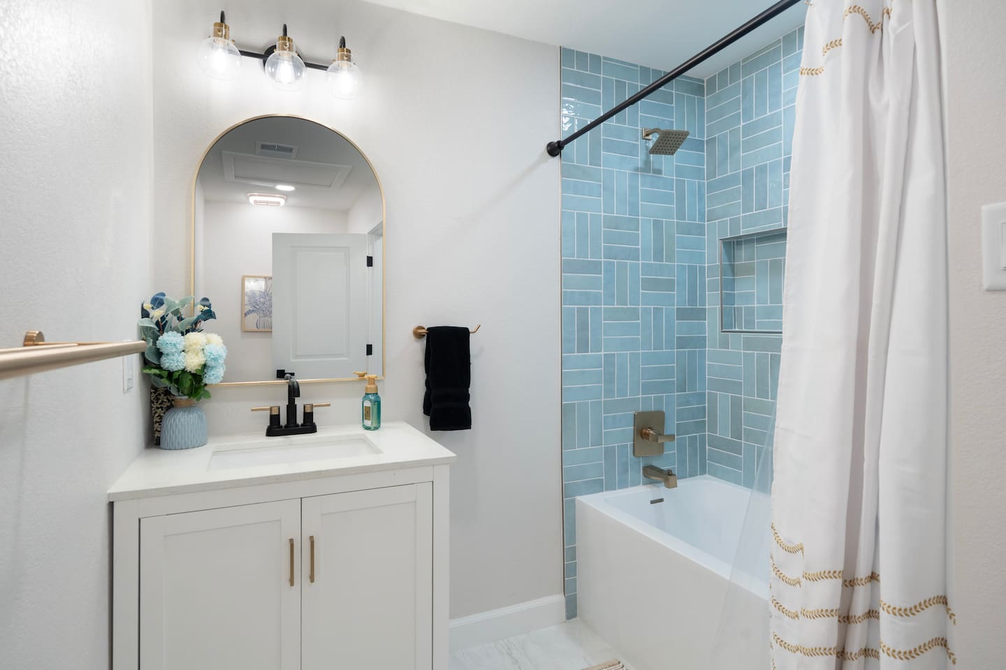 Bright, modern bathroom with designer tile shower, gold finishes, and spa-like feel