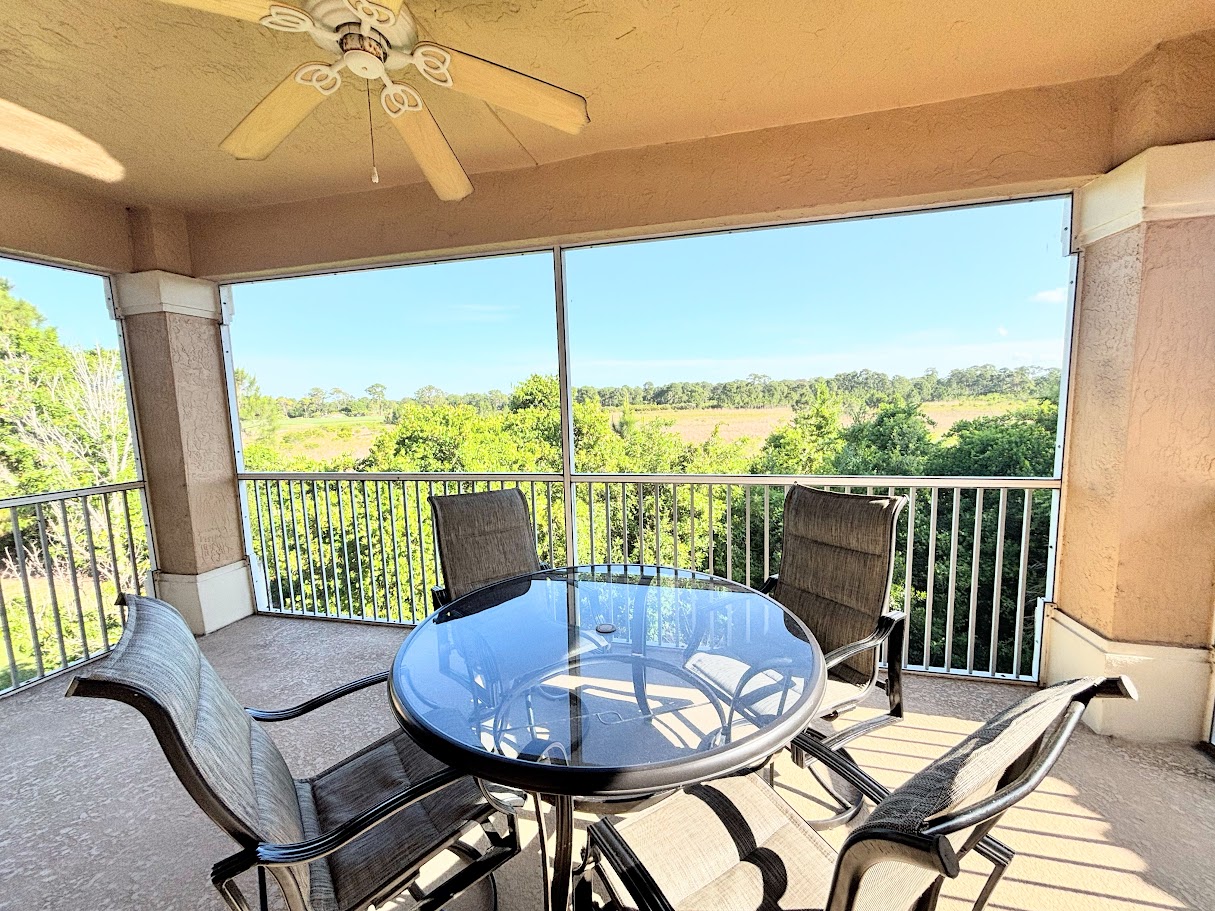 Private screened balcony with outdoor seating and peaceful views of the surrounding greenery.