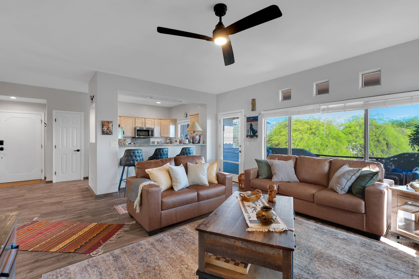 Spacious living room with leather sofas, coffee table, balcony access, barstools