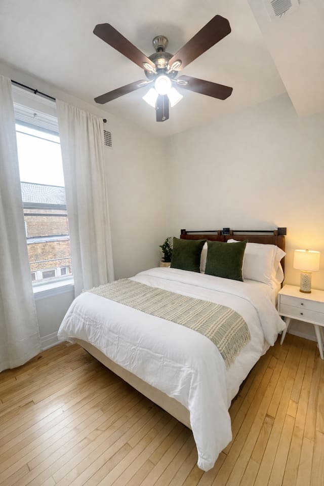 Comfortable bedroom with large windows and cozy bedding.