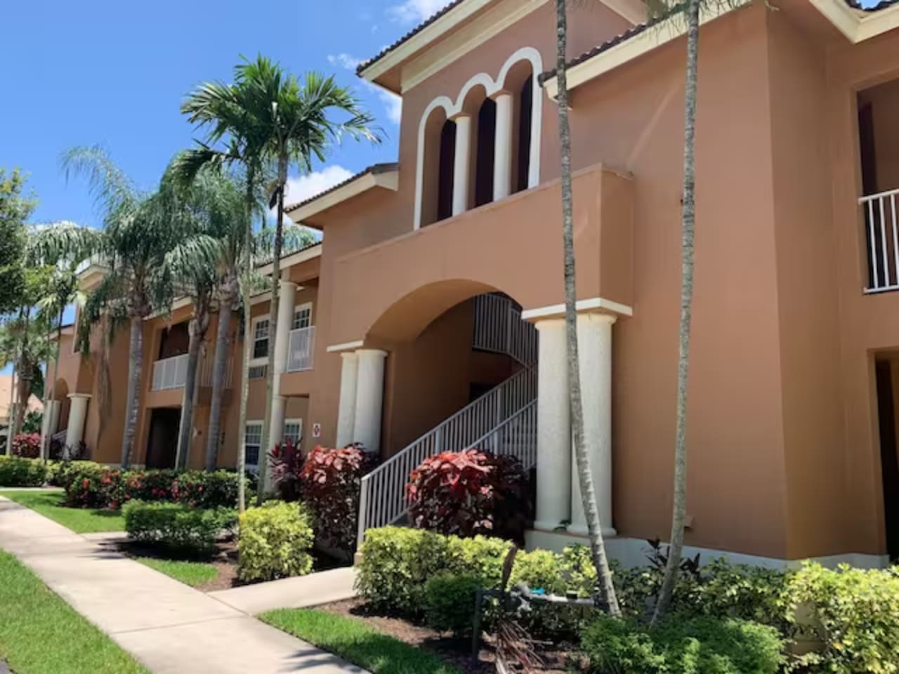 Exterior view of the building with tropical landscaping, covered walkways, and Florida-style architecture.