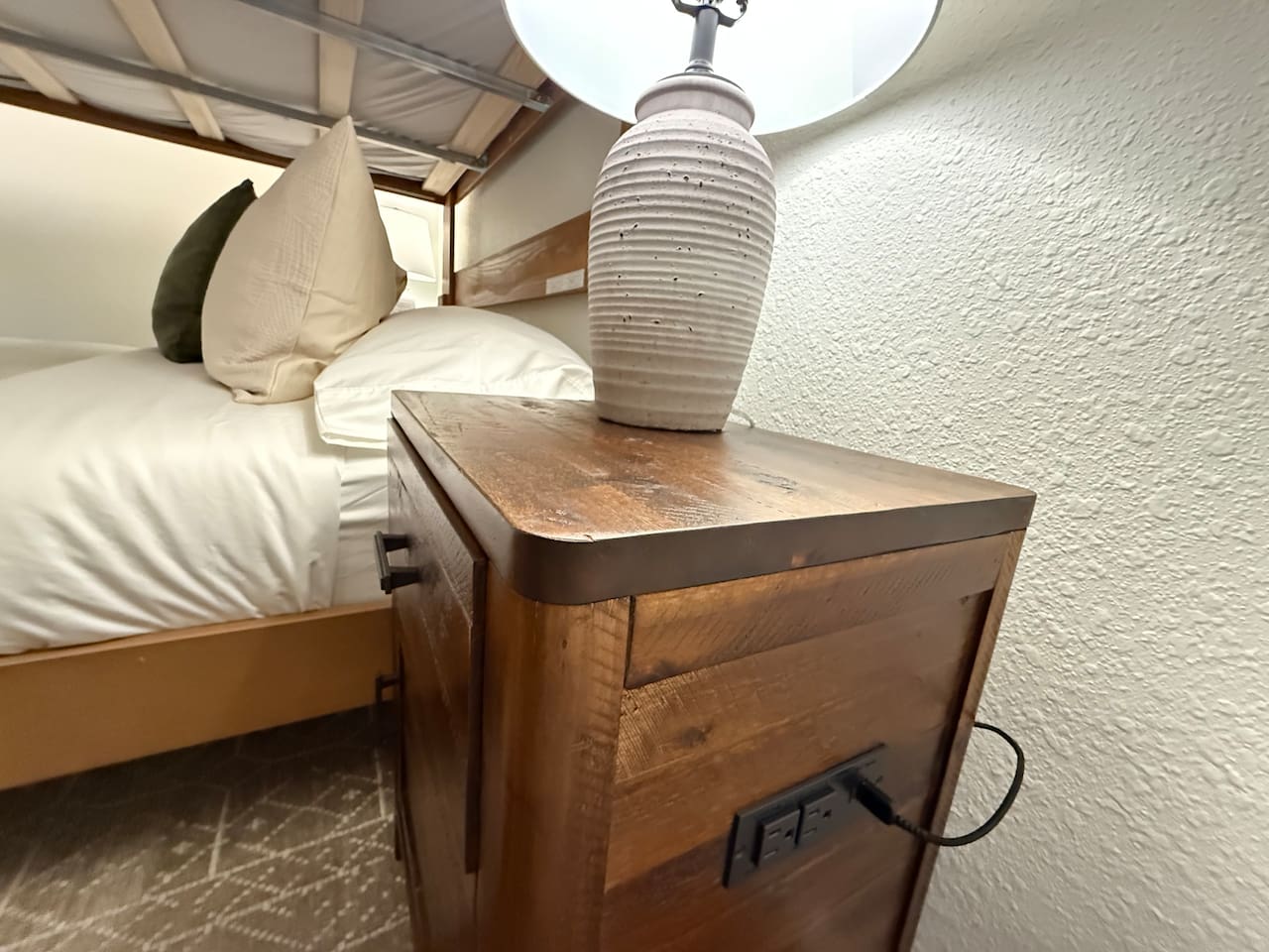 Nightstands with a lamp and electrical outlets and USB outlets on either side of the bed. 