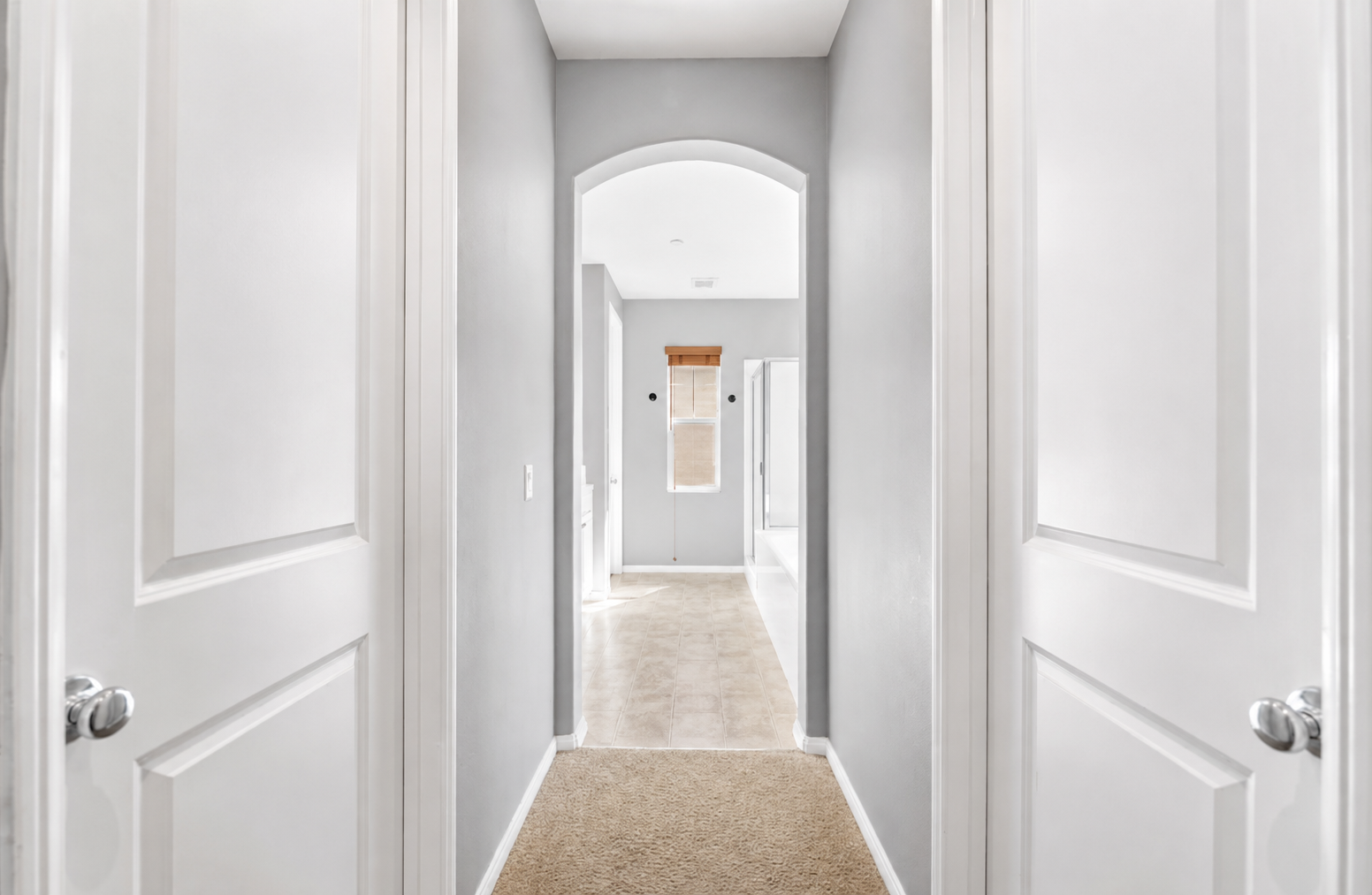 Hallway view with arched entry, soft carpet, and easy access between the bedrooms