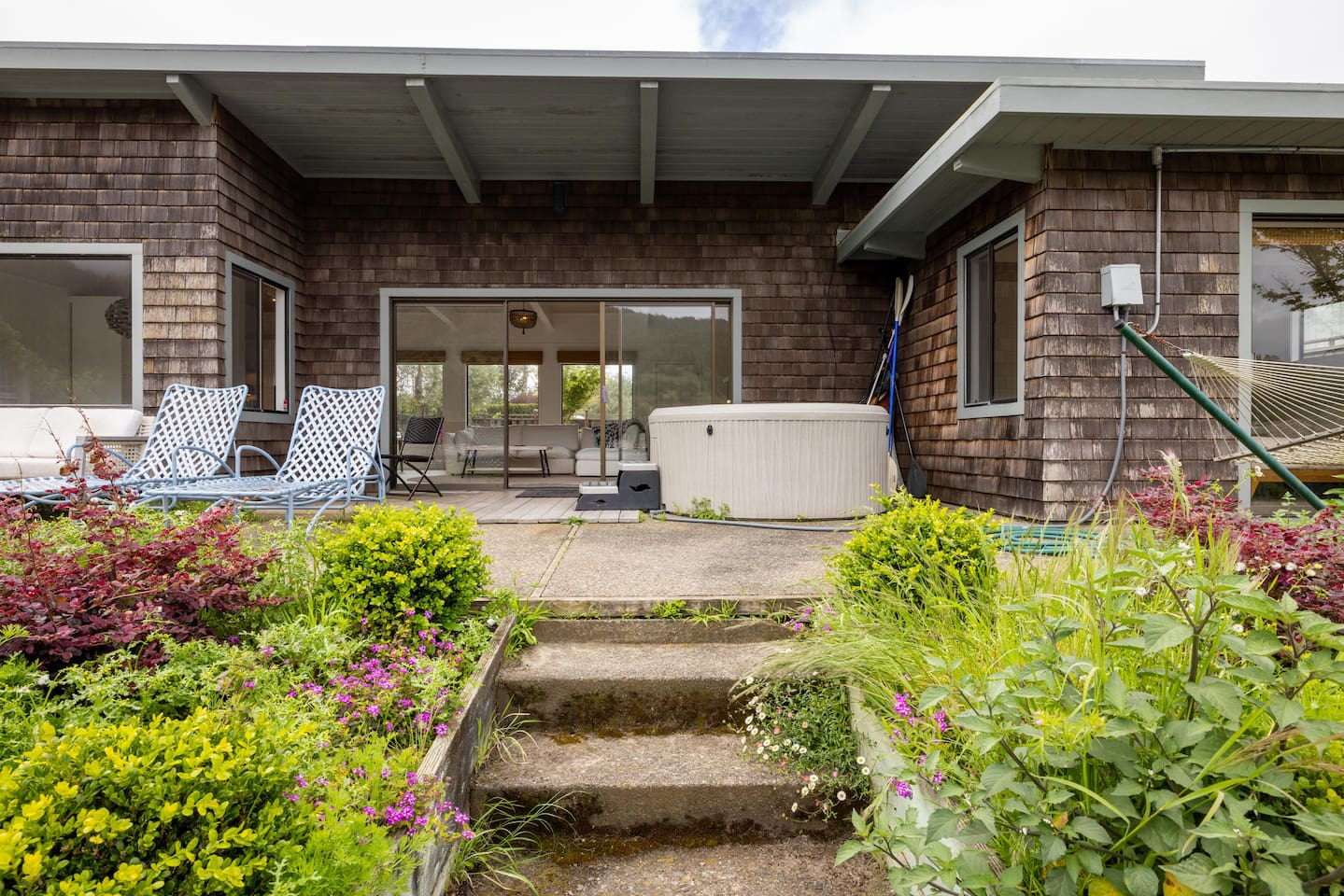 - Back patio with hot tub, lounge chairs, and beautiful garden landscaping  
- Steps lead directly from the house to this relaxing outdoor retreat  
- Perfect space to unwind and enjoy fresh air with a scenic waterfront view  
