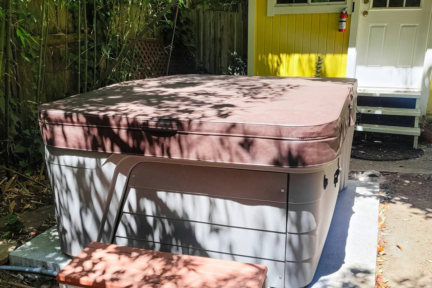 - Covered hot tub with secure insulated lid for year round relaxation  
- Located beside the cheerful yellow garden shed for added charm  
- Private setting surrounded by natural shade for peaceful soaking  