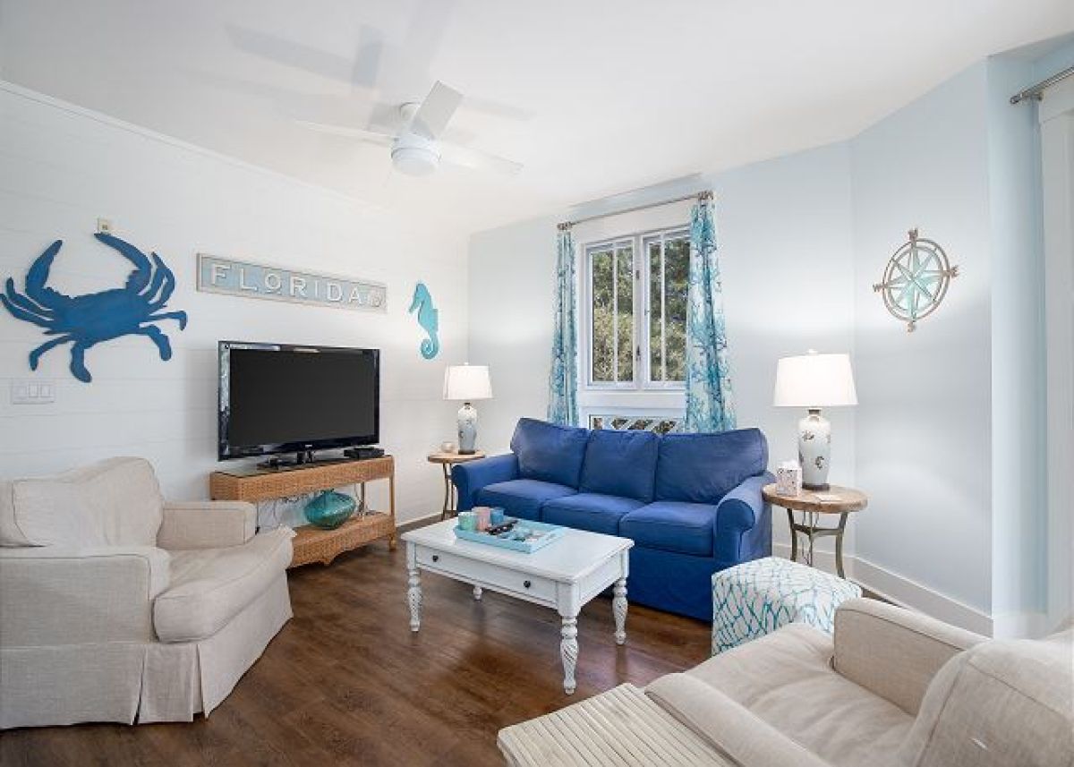 Living room seating area with HDTV, coastal wall art and a window to the resort gardens