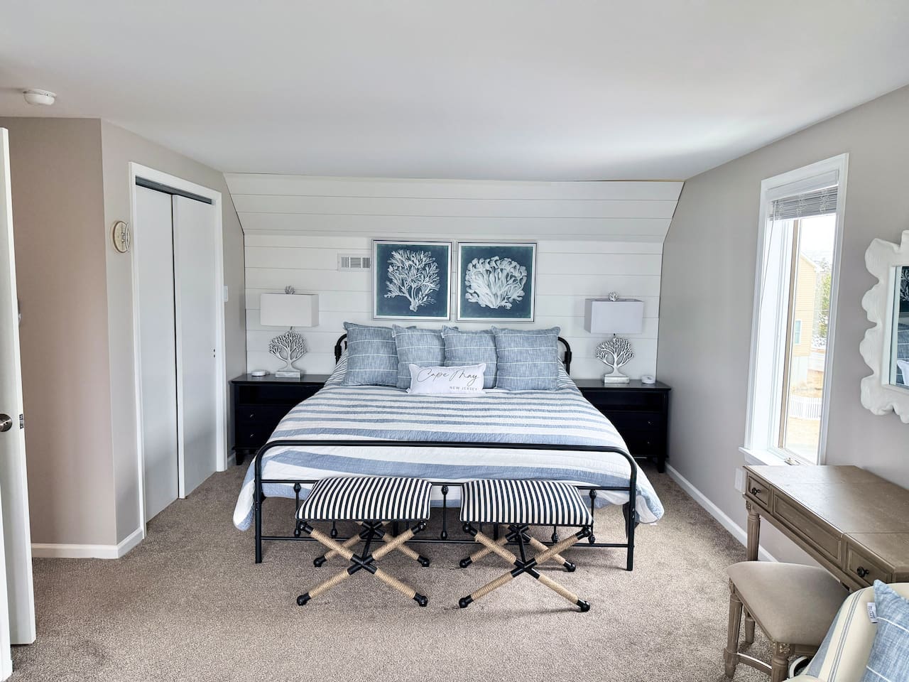 You will find a serene bedroom retreat designed with a calm, coastal aesthetic. The space features a cozy bed adorned with blue and white accents, framed by a charming shiplap wall, making it an ideal, restful sanctuary for your vacation.