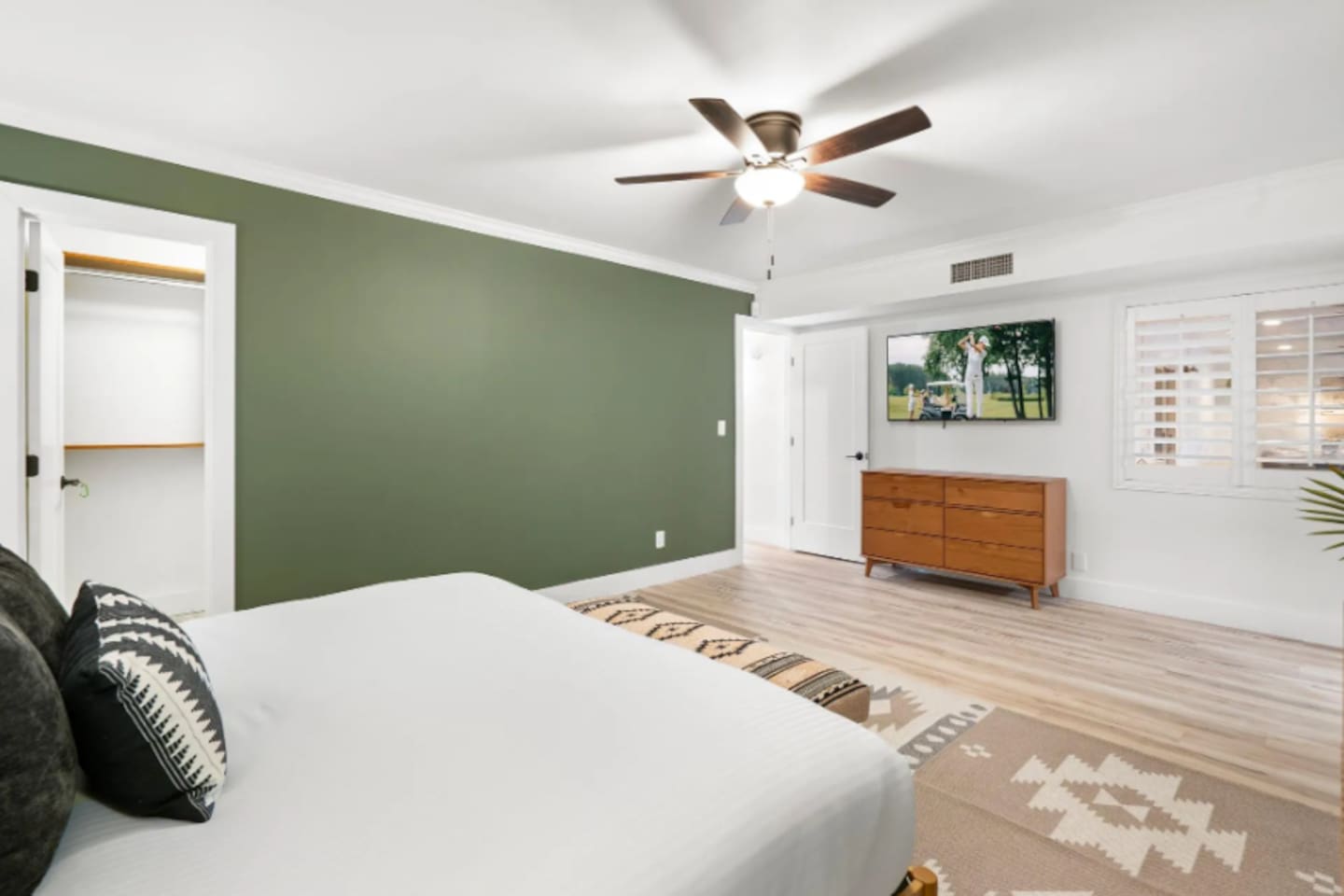 A deep olive accent wall grounds this bright, airy room, while a mid-century dresser and framed art add warmth. Walk-in closet space and soft natural light make it an easy retreat for anyone needing a little quiet.
