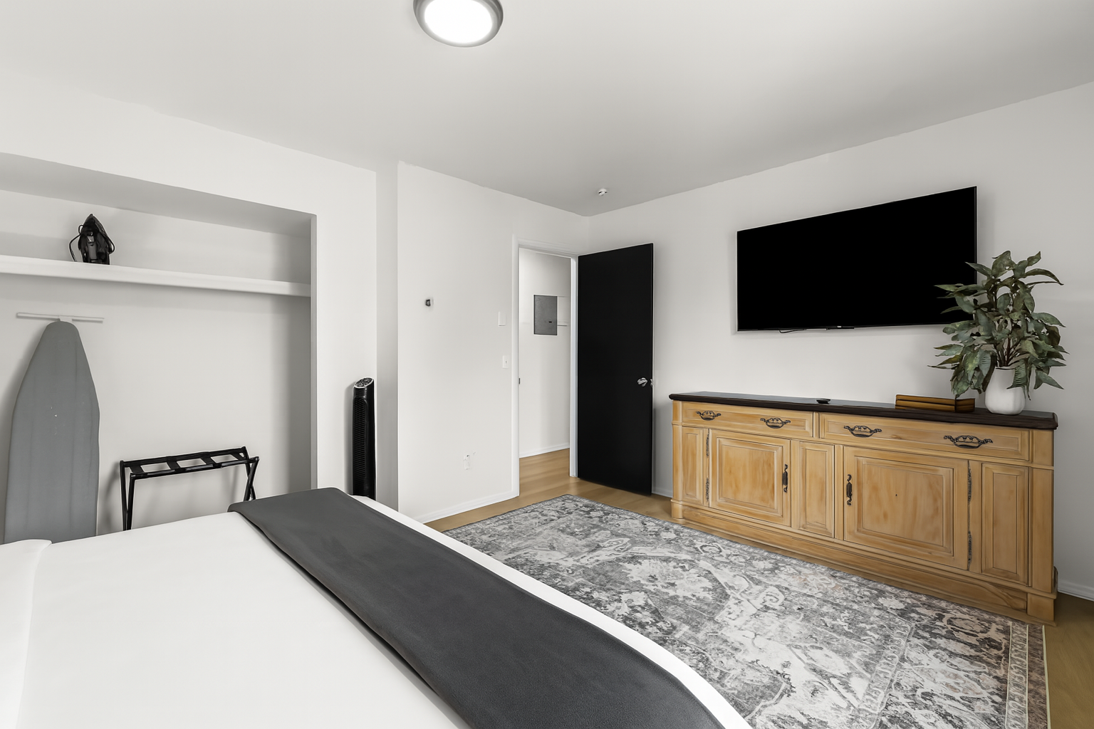 Wide view of the primary bedroom featuring a Smart TV, dresser, and blackout curtains for comfort and privacy.