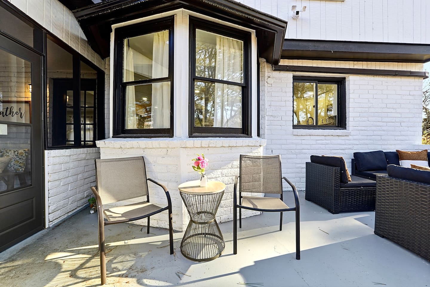 Inviting patio with black outdoor furniture, beige chairs, and a propane grill. A great space to relax, dine outside, or enjoy time with friends and family.