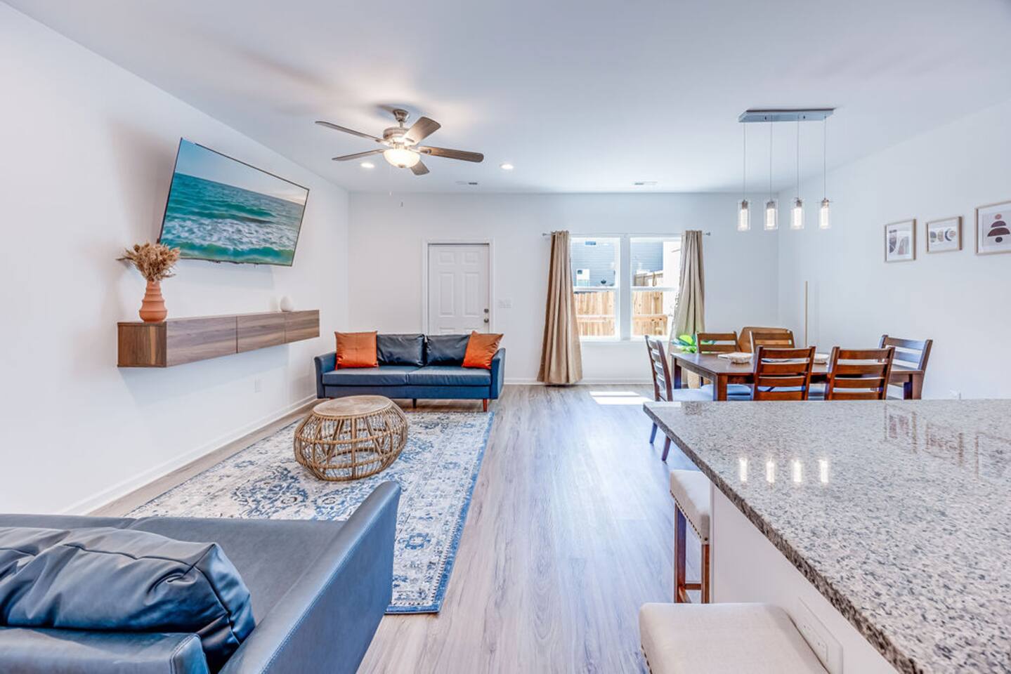 Relax in this spacious, open-concept living and dining area featuring two cozy couches, a TV, a dining table under a ceiling fan, and plenty of room to unwind
