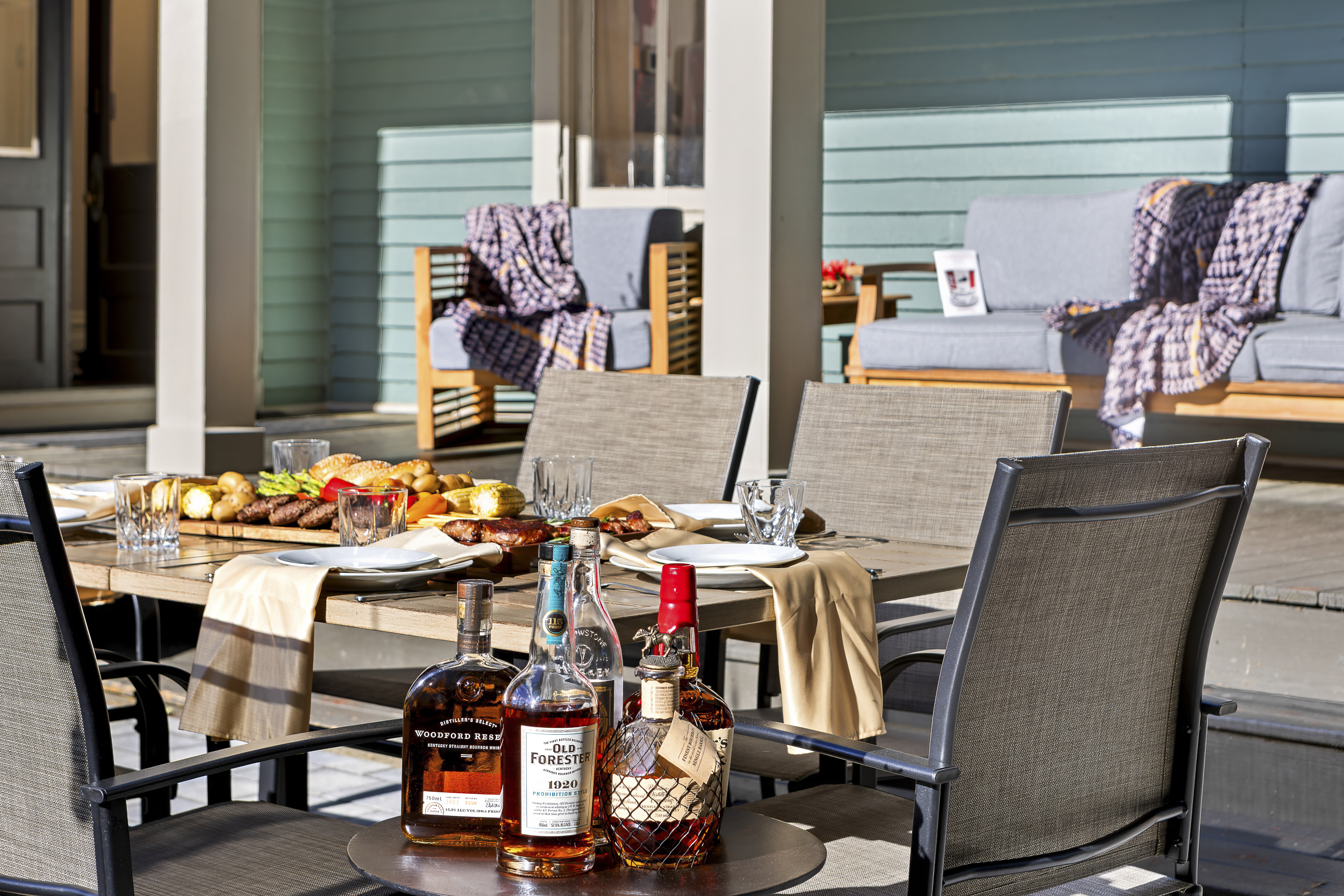 The covered back porch doubles as an outdoor dining room, complete with Woodford, Old Forester, and a table made for good company.