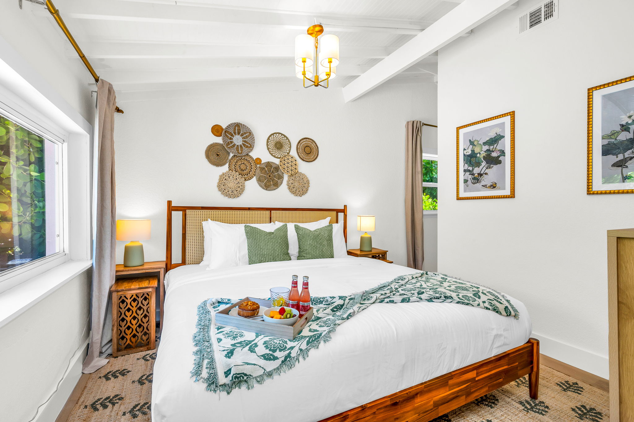 Serene ensuite primary king suite featuring a plush bed with luxury linens, vaulted ceilings with exposed beams, and elegant coastal décor. Includes a spacious walk-in closet with washer and dryer for added convenience and comfort.