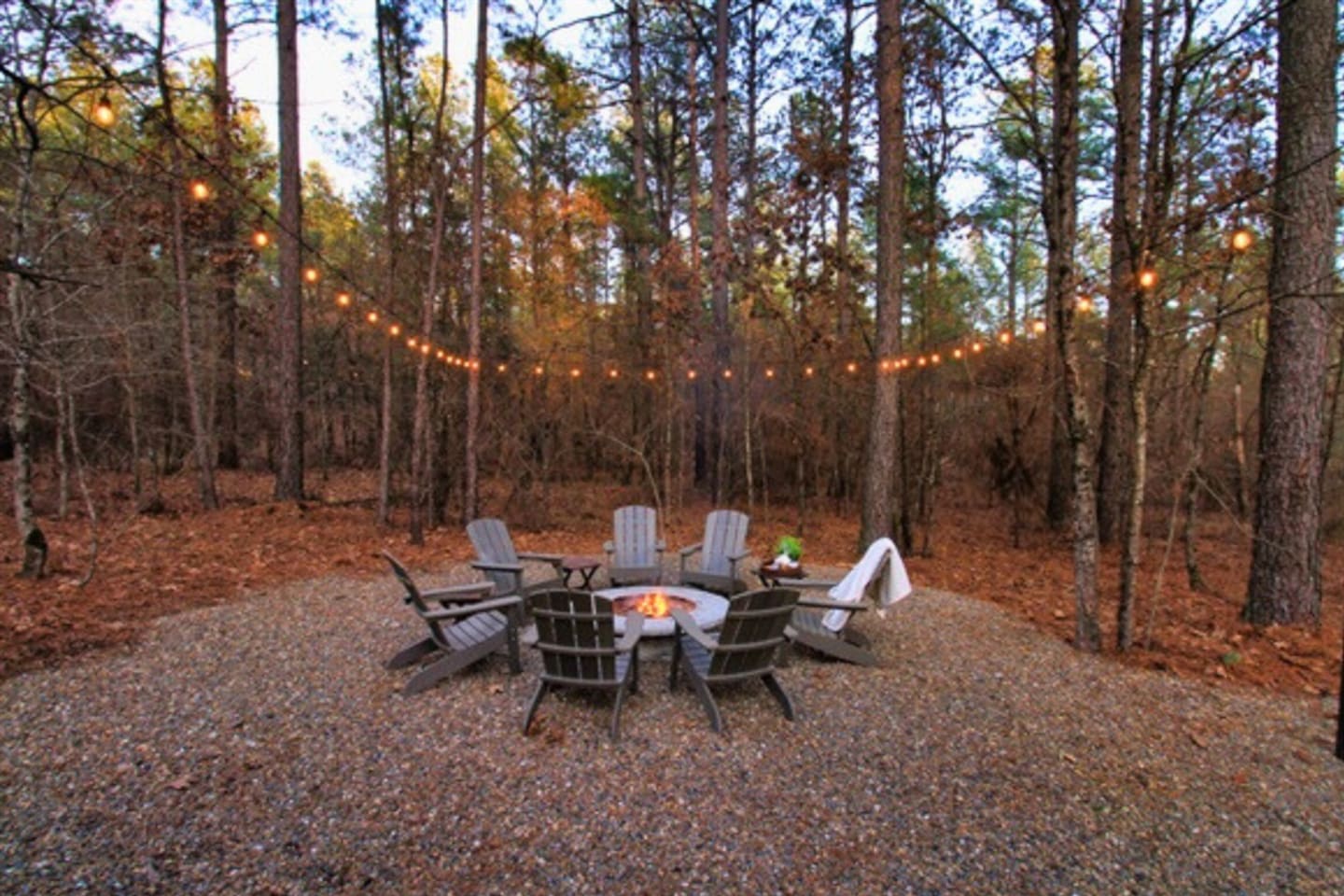 The outdoor fire pit with Adirondack chairs is perfect for relaxing nights in the forest.