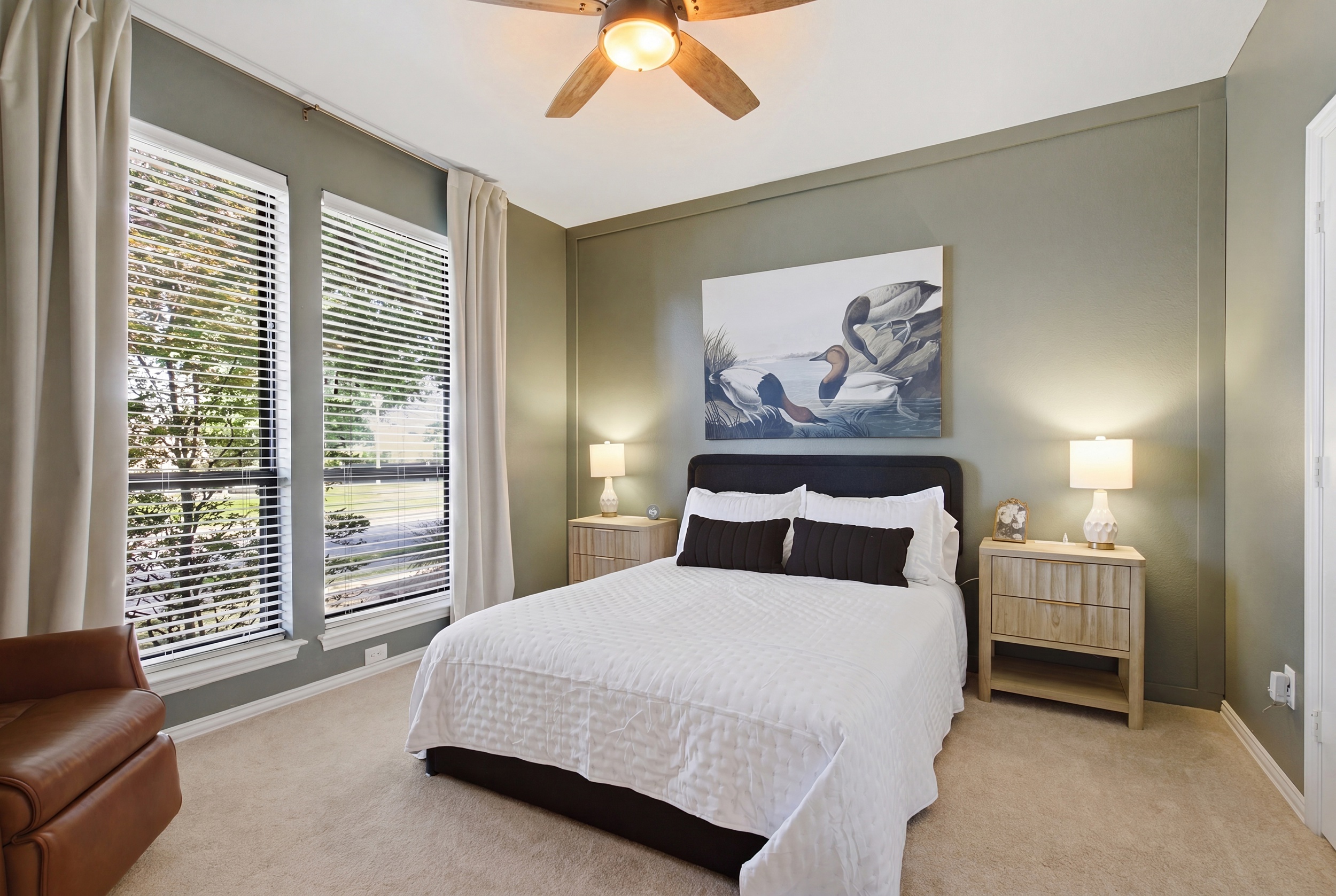 Guest Bedroom 2 with a Queen Bed, 55-inch Smart TV, leather recliner, and a dedicated workspace with desk and office chair, ideal for remote work or evening downtime.
