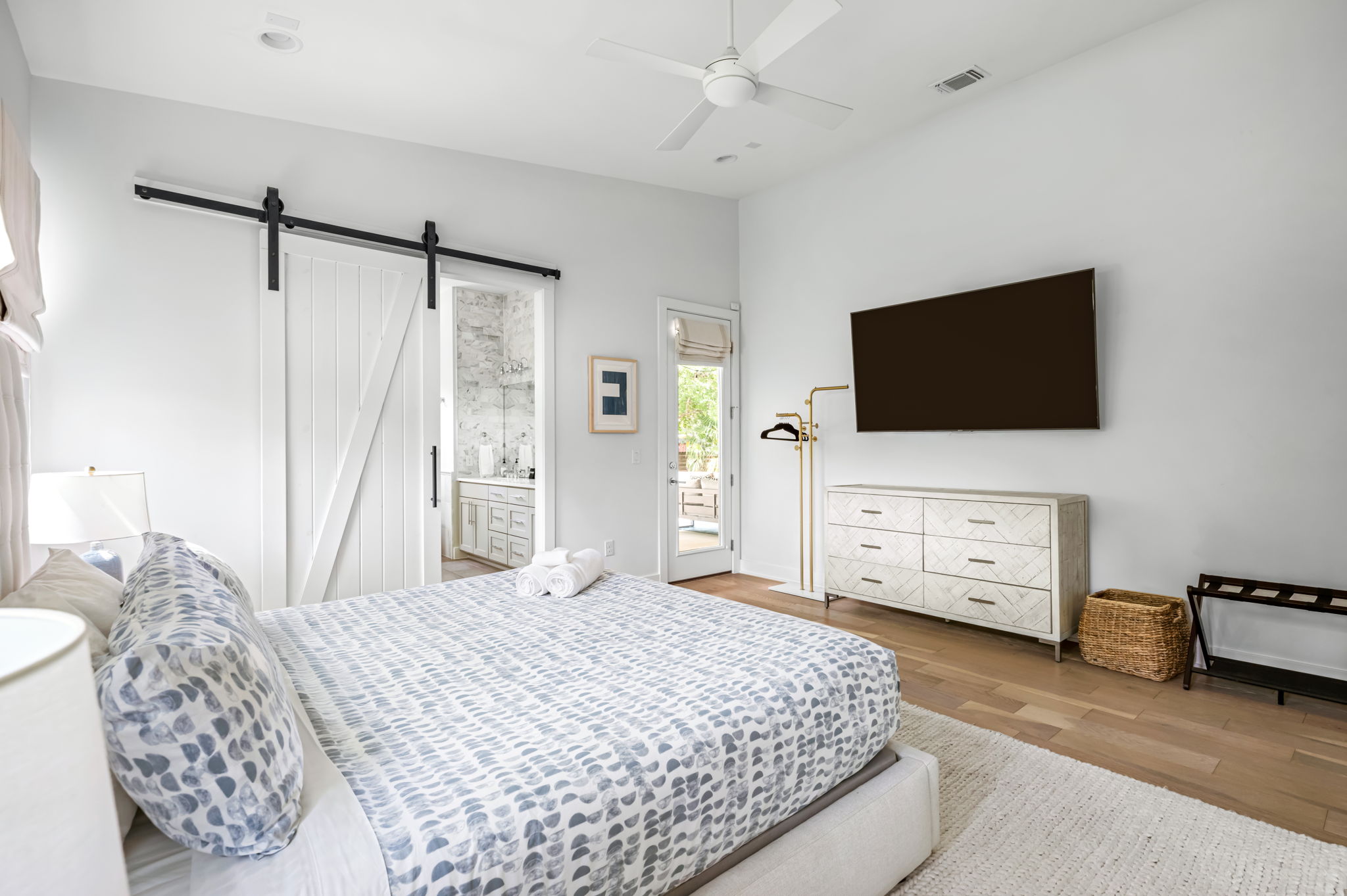 Cozy bedroom featuring a plush bed, wall-mounted TV, and stylish barn door accents — comfort meets modern design.