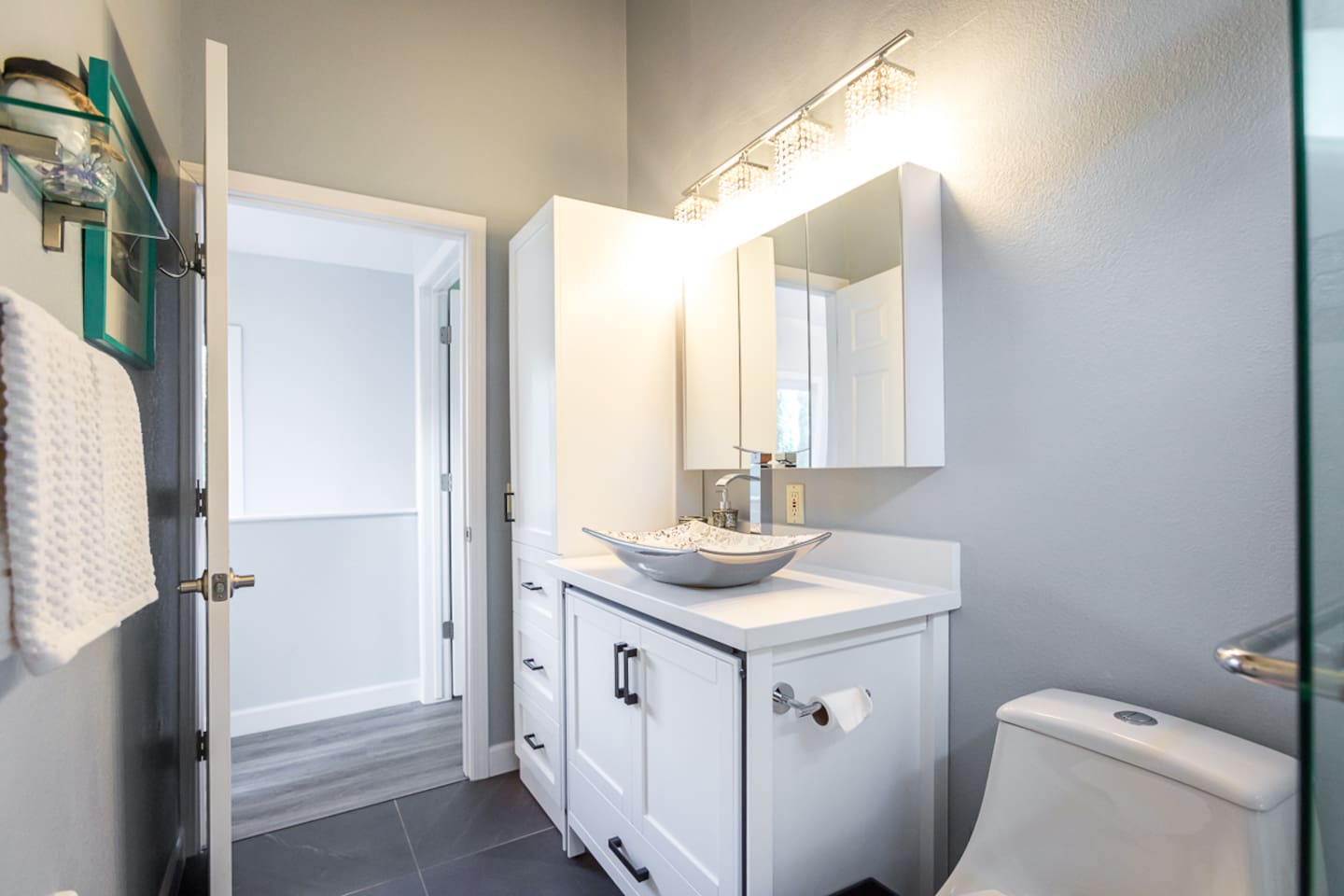 - Bright bathroom with vessel sink, sleek vanity, & mirrored storage cabinet under soft modern lighting
- Chrome fixtures & fresh white cabinetry for a clean, inviting feel
- Neutral tones and natural light create a relaxing spa inspired atmosphere