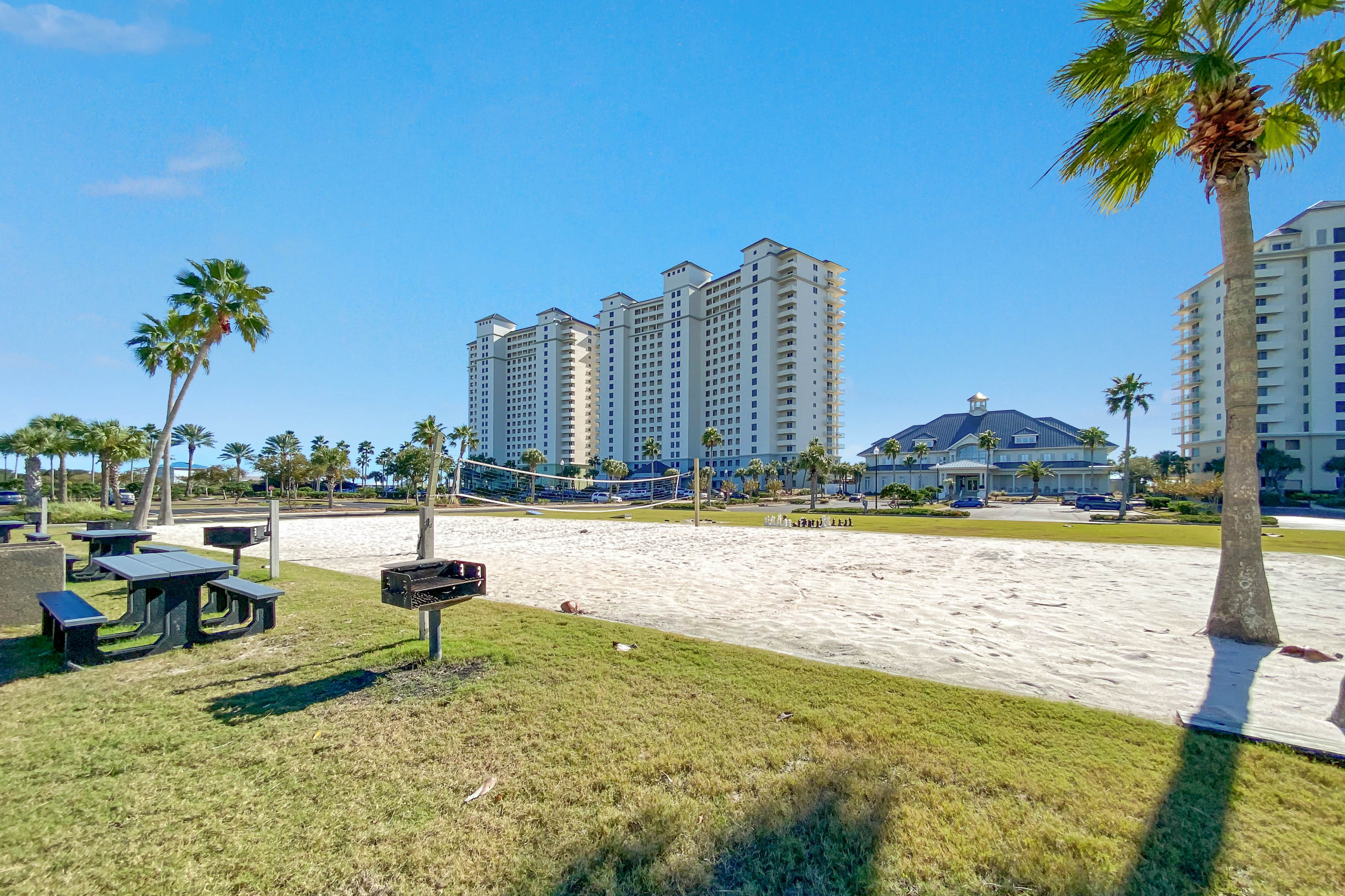 Expansive views of the property showcasing recreational areas, including a beach volleyball court, surrounded by manicured lawns and swaying palm trees.