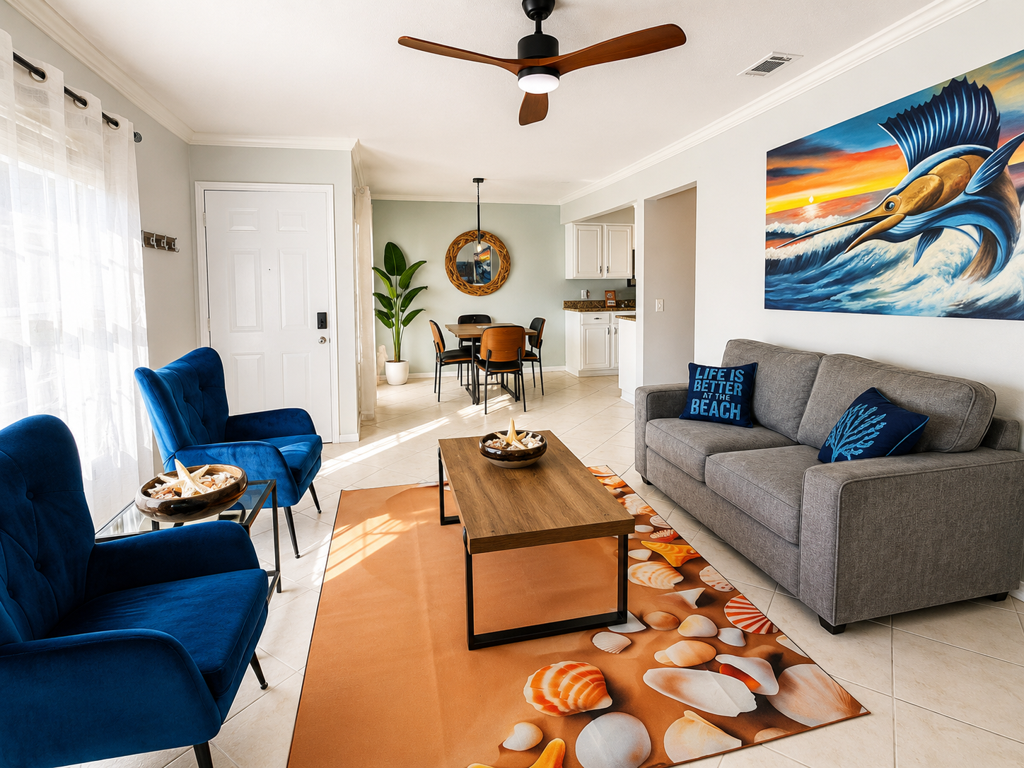 Bright coastal living room with gray sofa, blue armchairs, and sailfish artwork.
